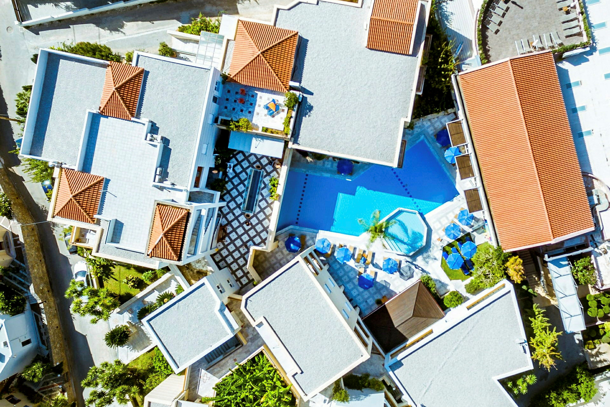Flyfoto av et hotellområde med bygninger og et basseng. (AI-generert tekst)