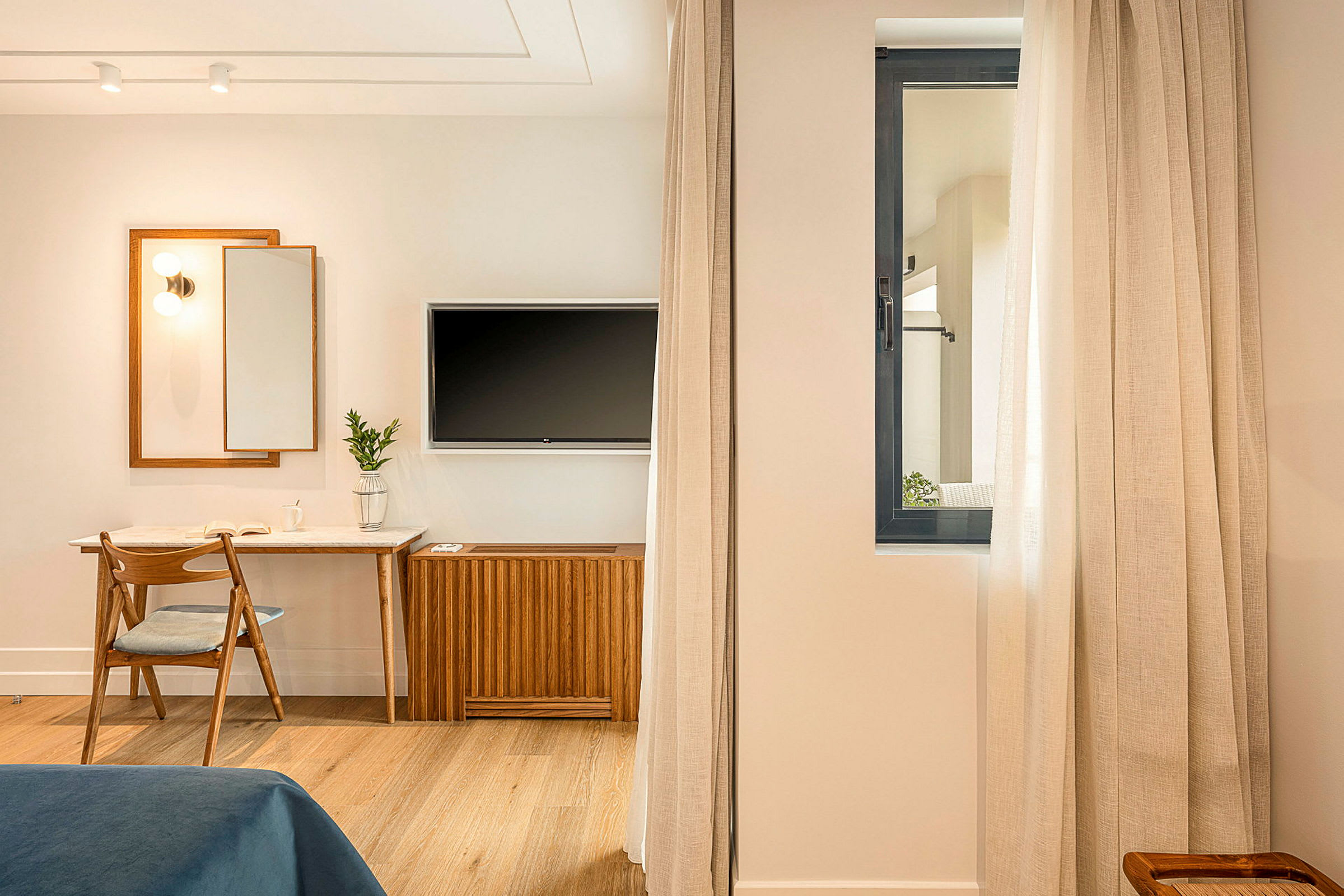 Rom med skrivebord, stol, speil og veggmontert TV. (AI-generert tekst)
