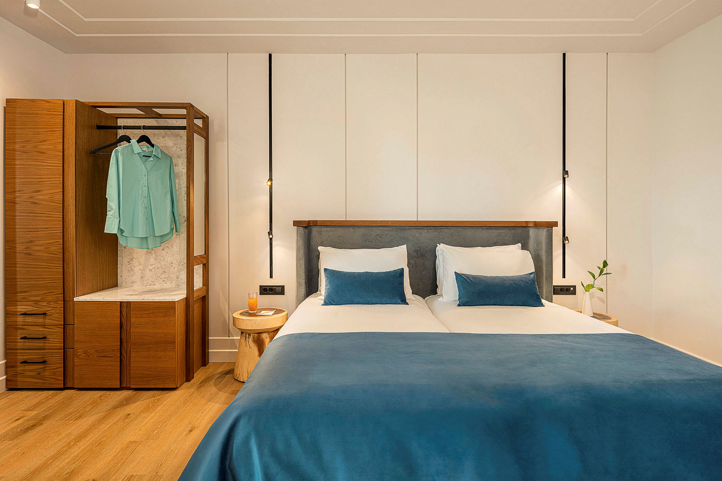 To enkeltsenger med blå sengetepper og puter i et moderne hotellrom. (AI-generert tekst)