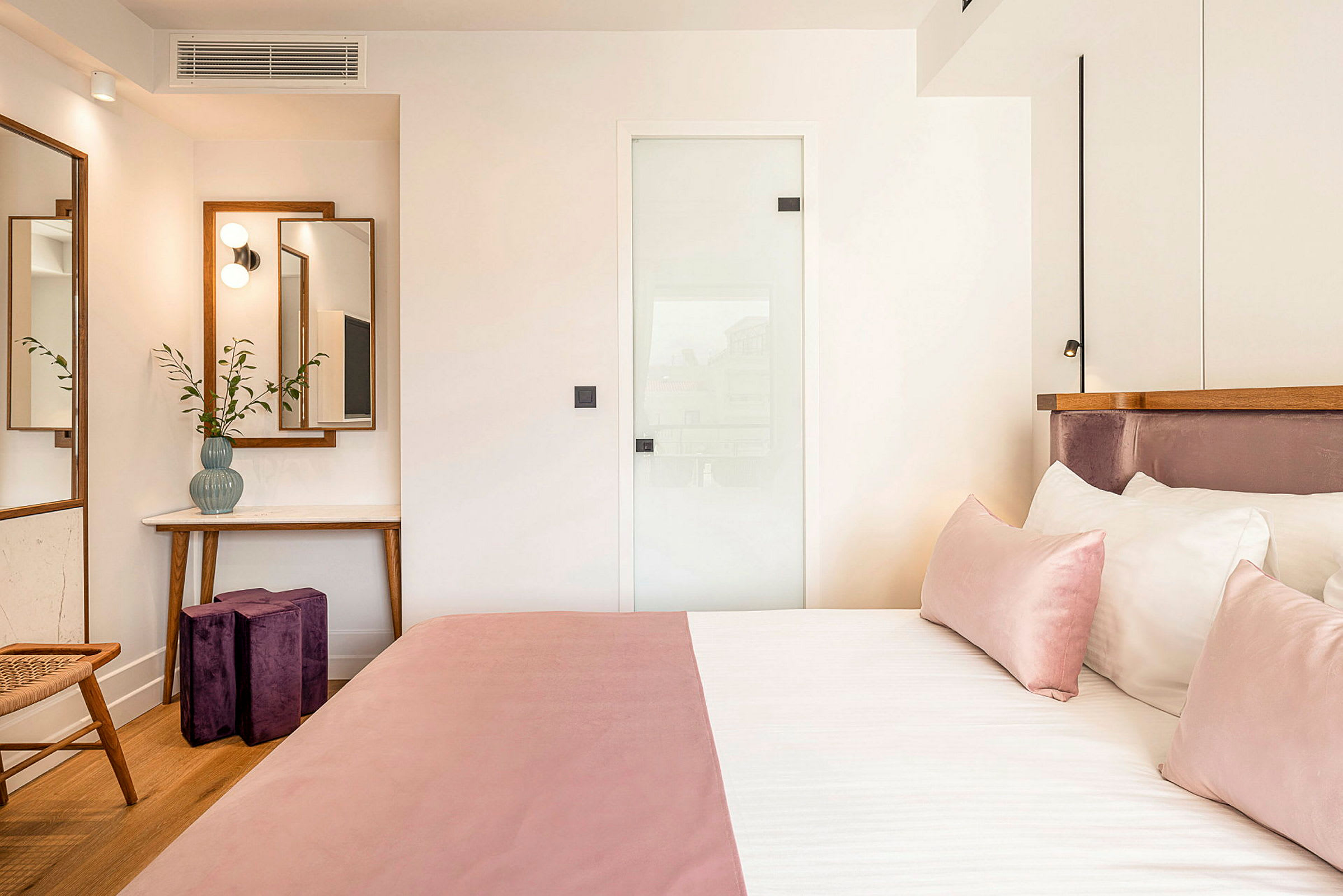 Et hotellrom med rosa sengetøy og moderne interiør. (AI-generert tekst)
