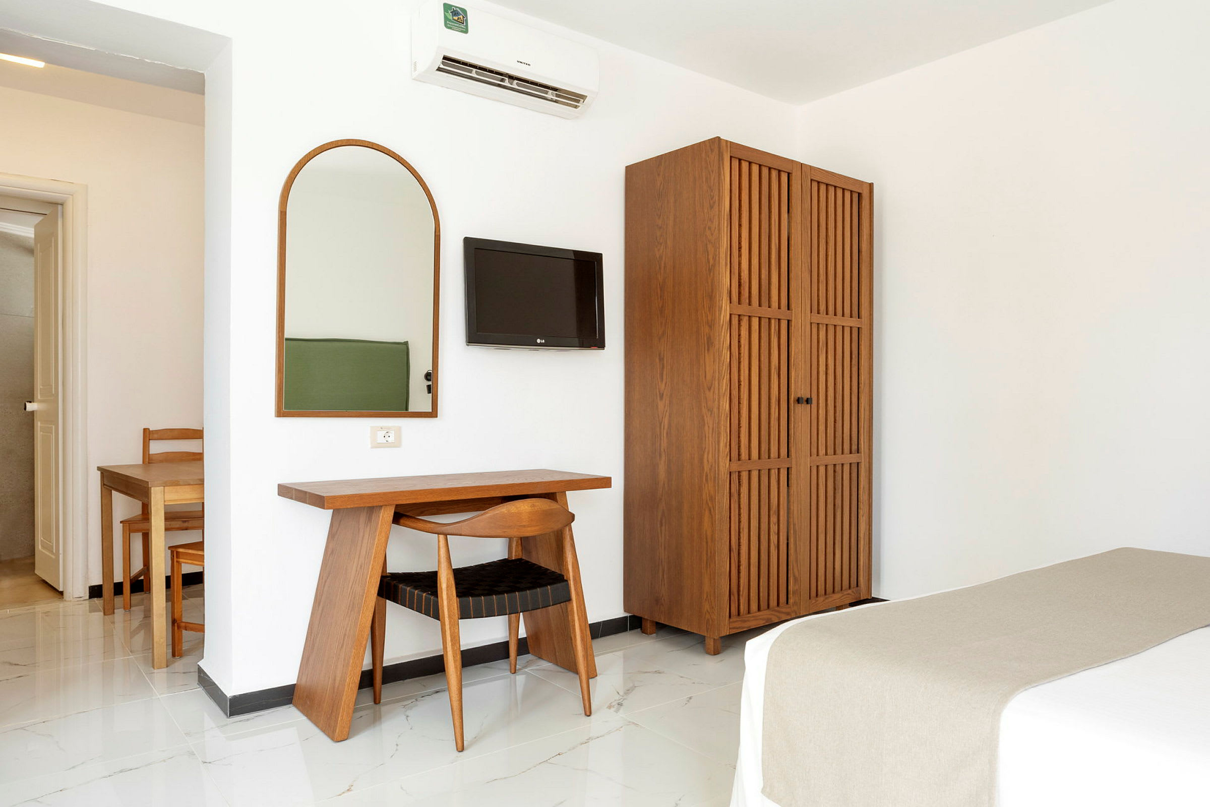 Et hotellrom med trebord, stol, speil, TV og garderobe. (AI-generert tekst)