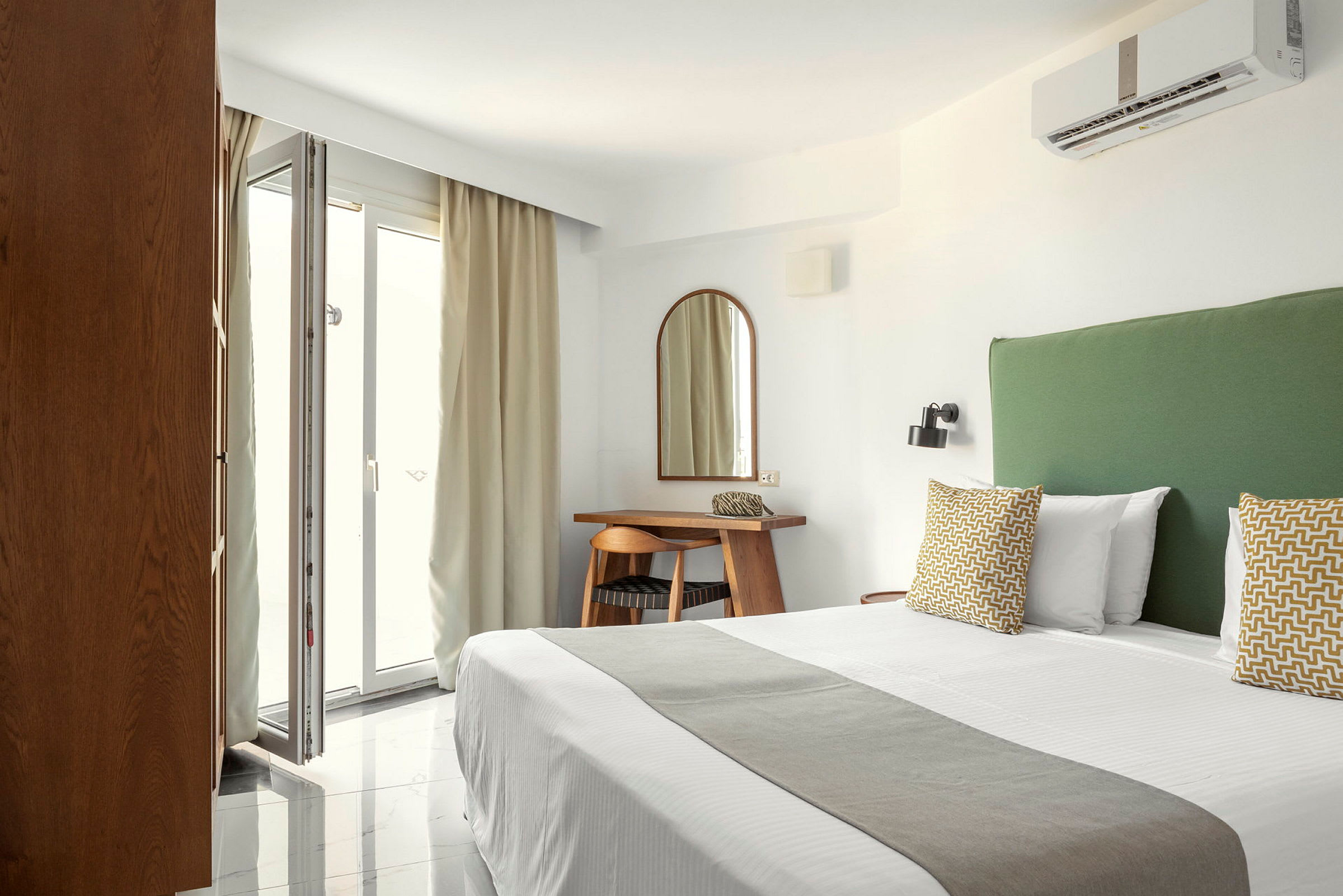 Hotellrom med seng, grønn sengegavl og skrivebord ved et speil. (AI-generert tekst)