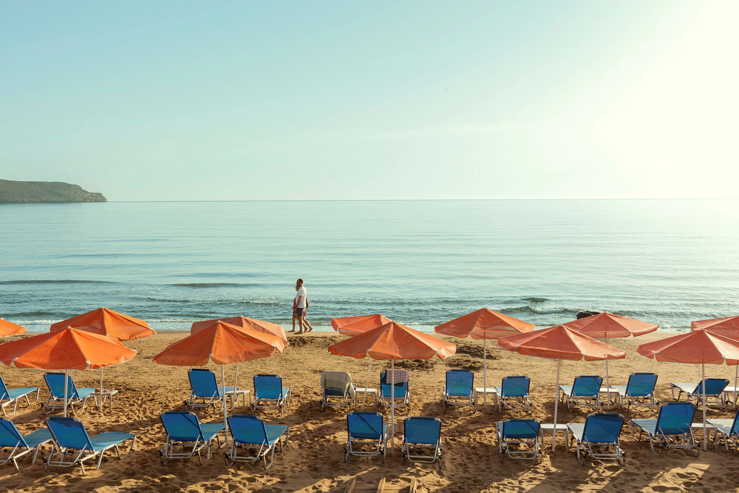 Solstoler og parasoller på en strand ved havet. (AI-generert tekst)