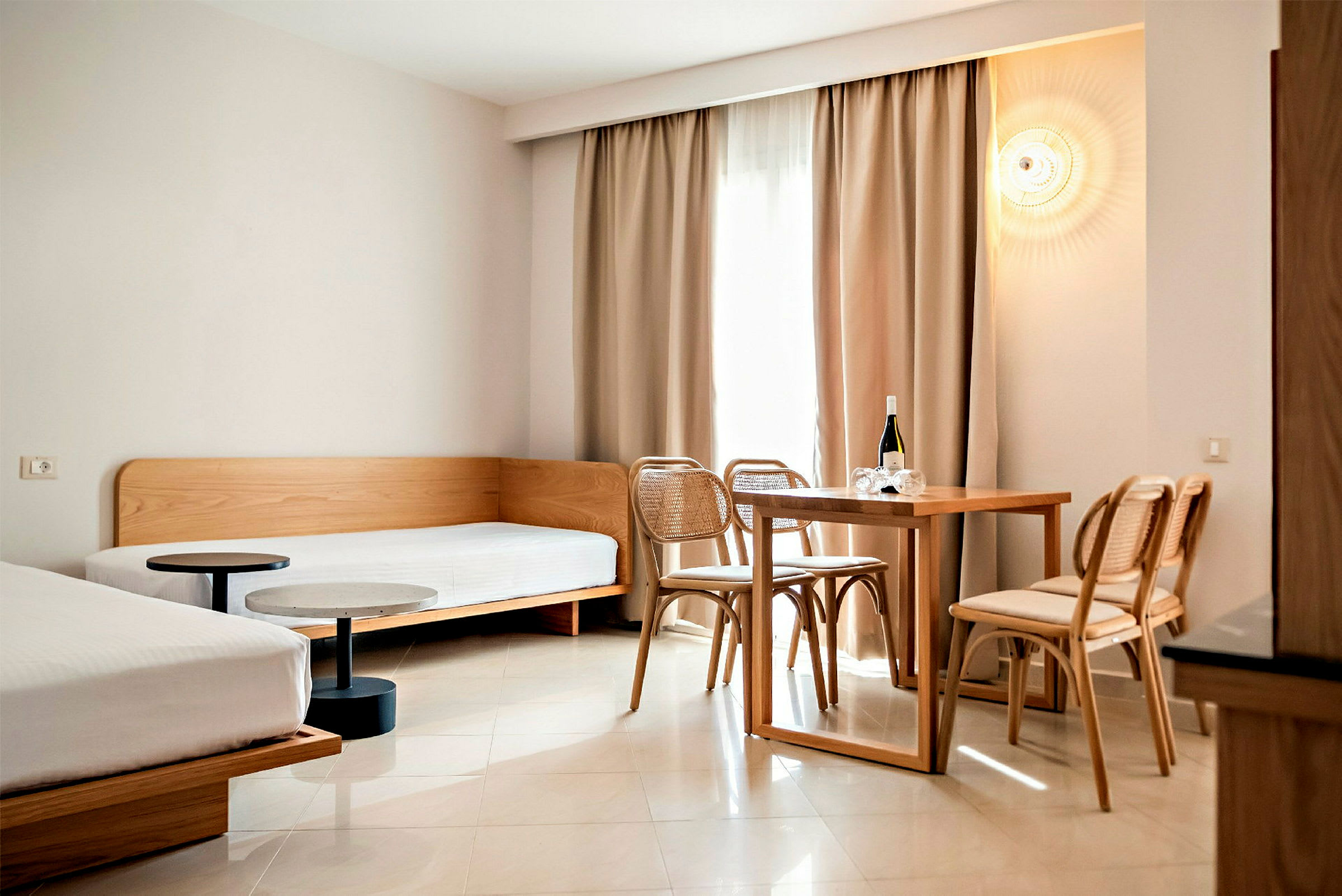 Et moderne innredet hotellrom med to senger og et spisebord med stoler. (AI-generert tekst)