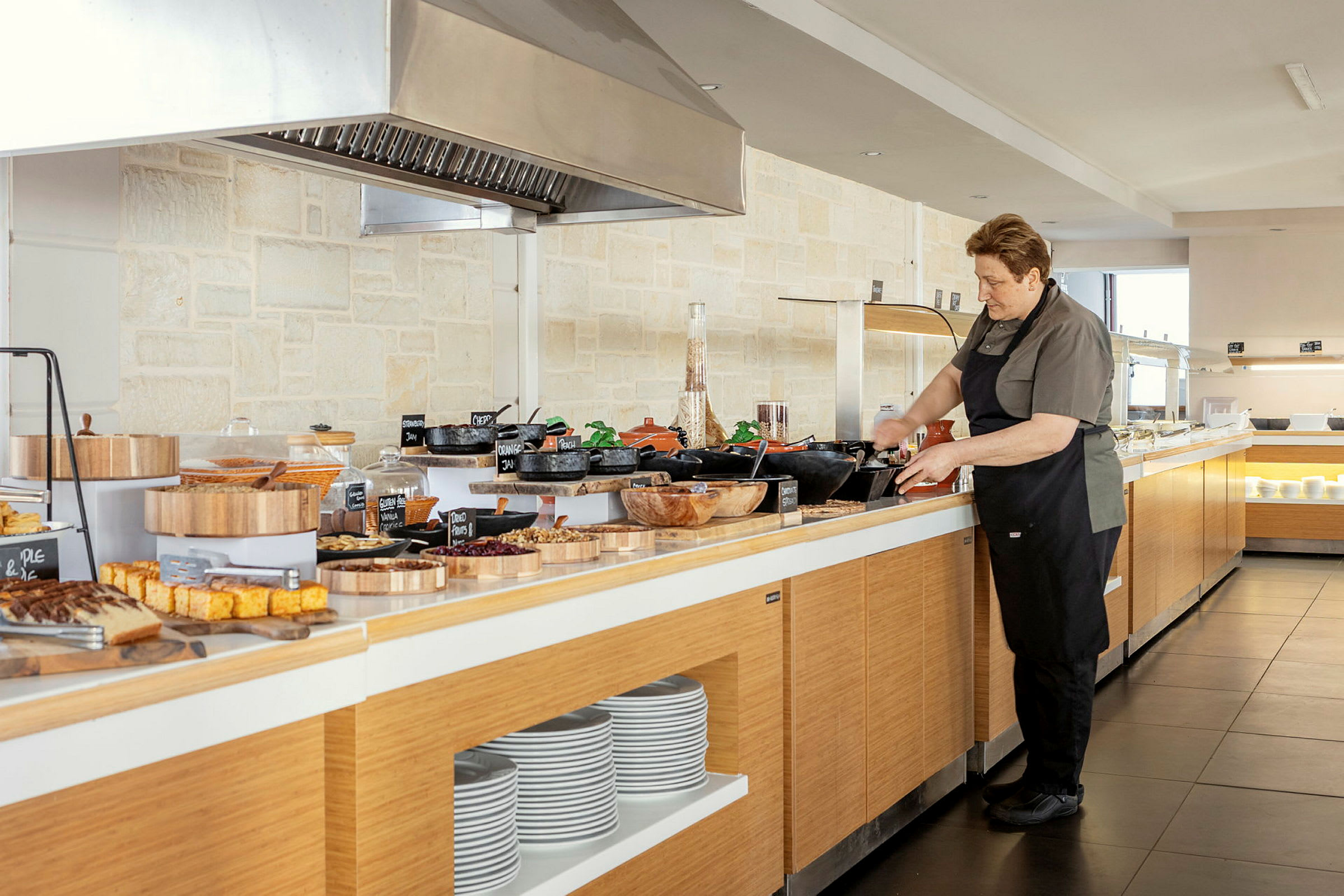 En person står ved en buffet med forskjellige retter og tallerkener. (AI-generert tekst)