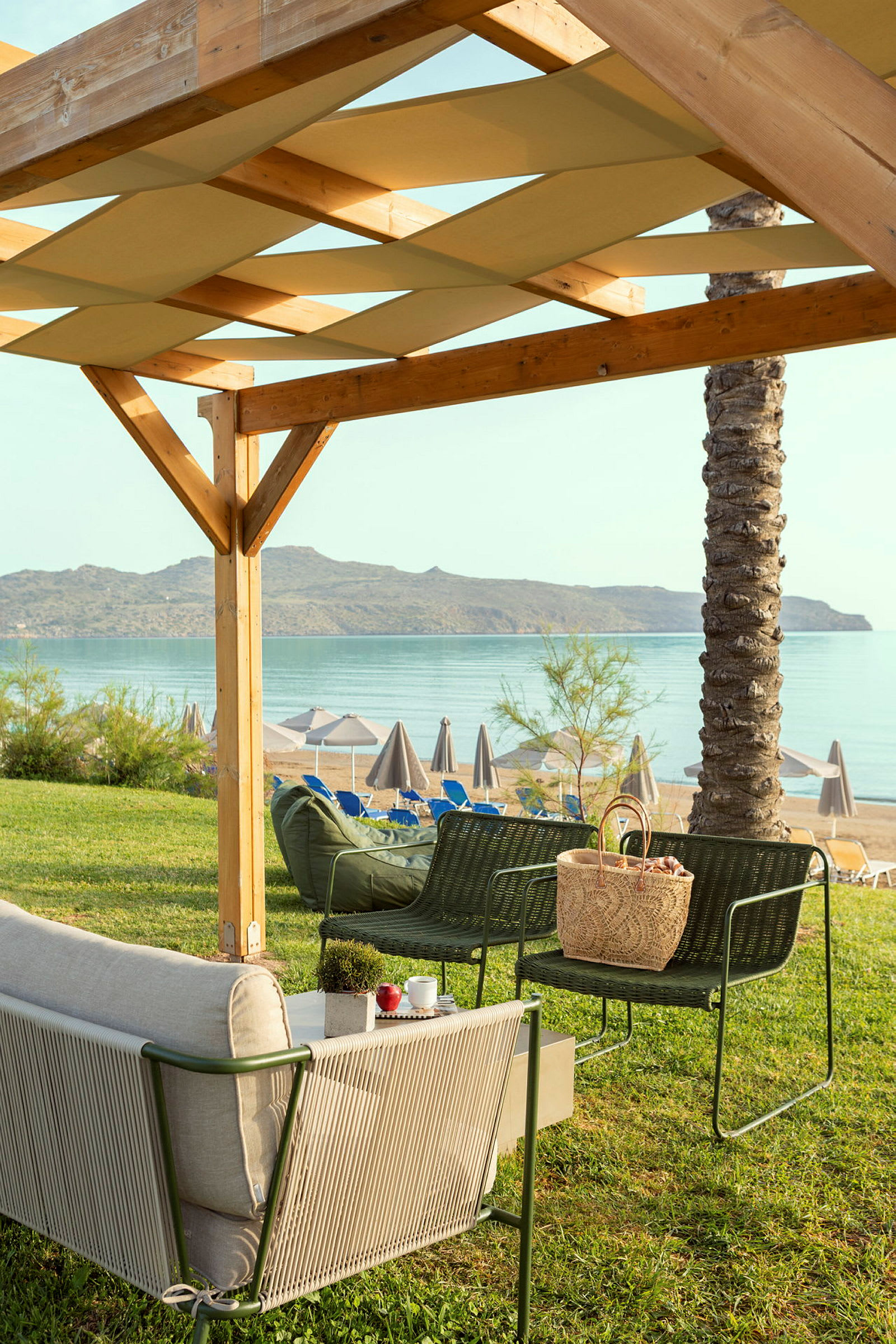 Hagemøbler under en trepergola med utsikt over stranden og havet. (AI-generert tekst)