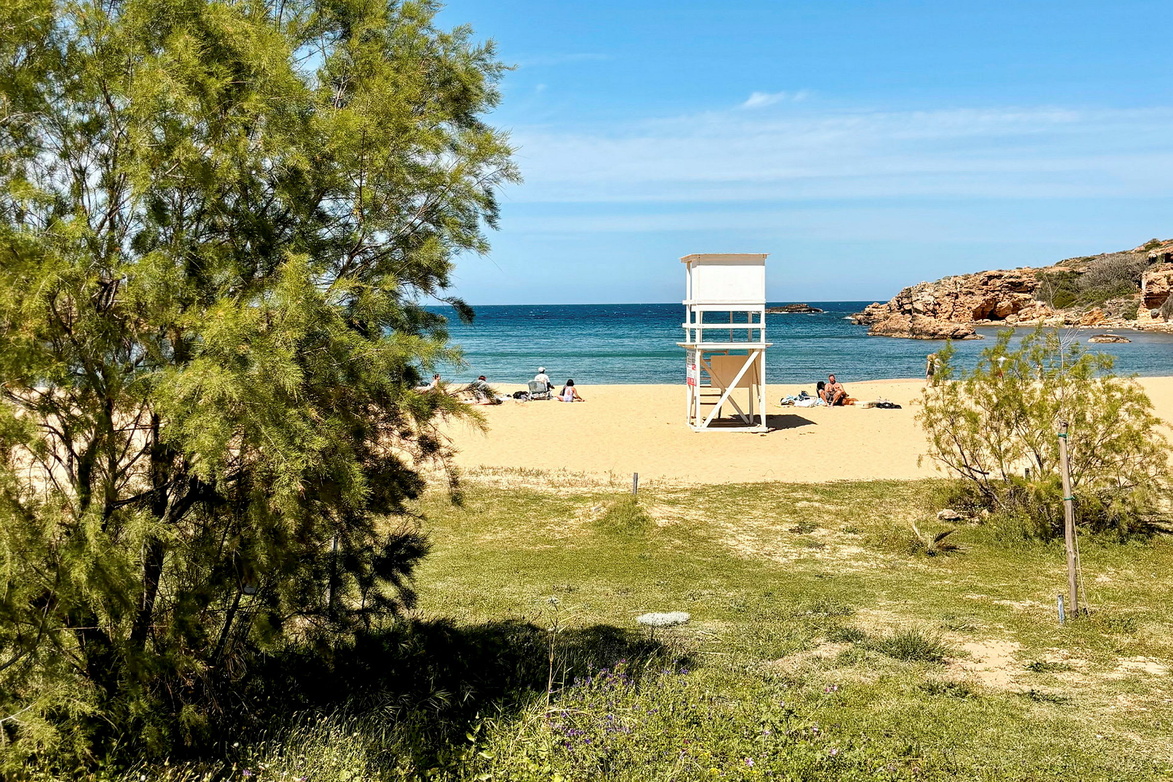 En sandstrand med badegjester, et livreddertårn og utsikt mot havet. (AI-generert tekst)