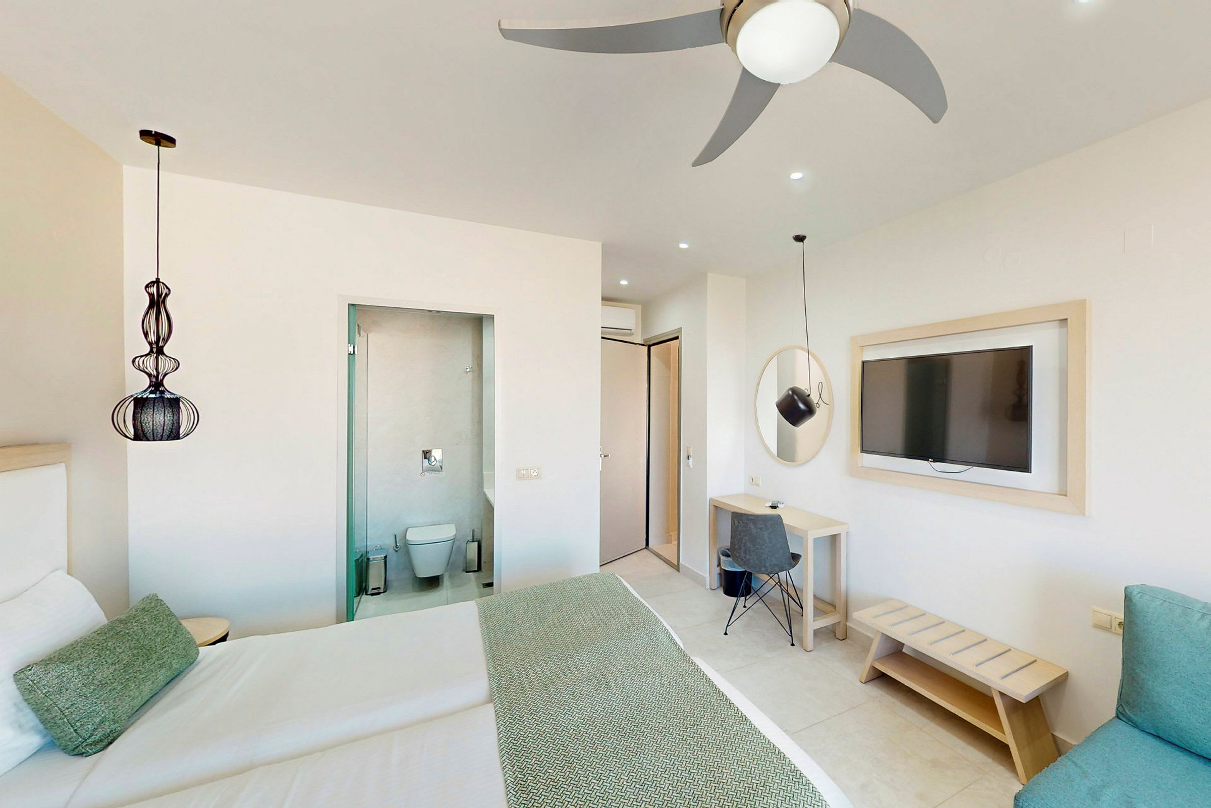 Hotellrom med en dobbeltseng, et skrivebord, en veggmontert TV og inngang til badet. (AI-generert tekst)