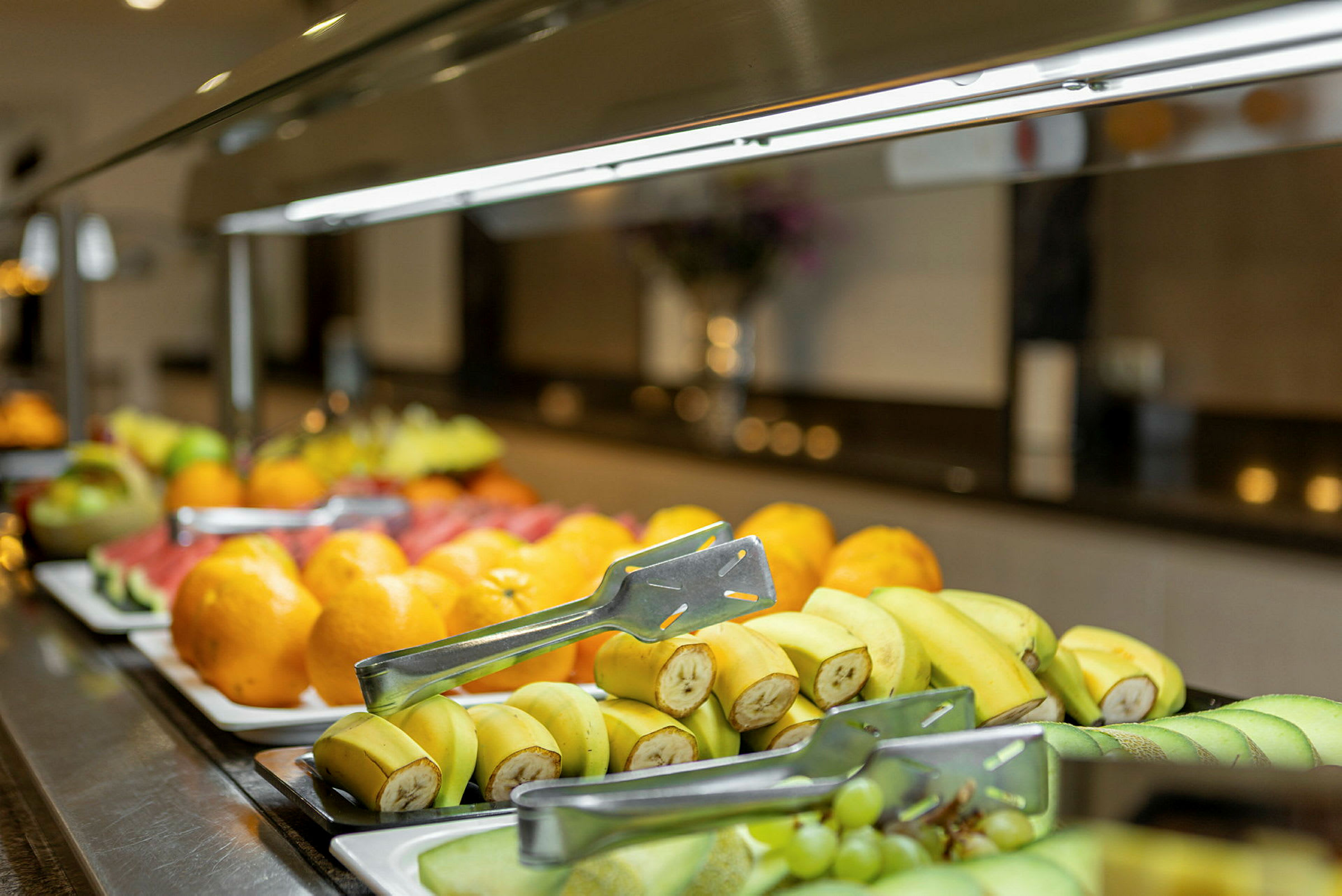 Et buffébord med forskjellige frukter, inkludert bananer, druer og appelsiner. (AI-generert tekst)