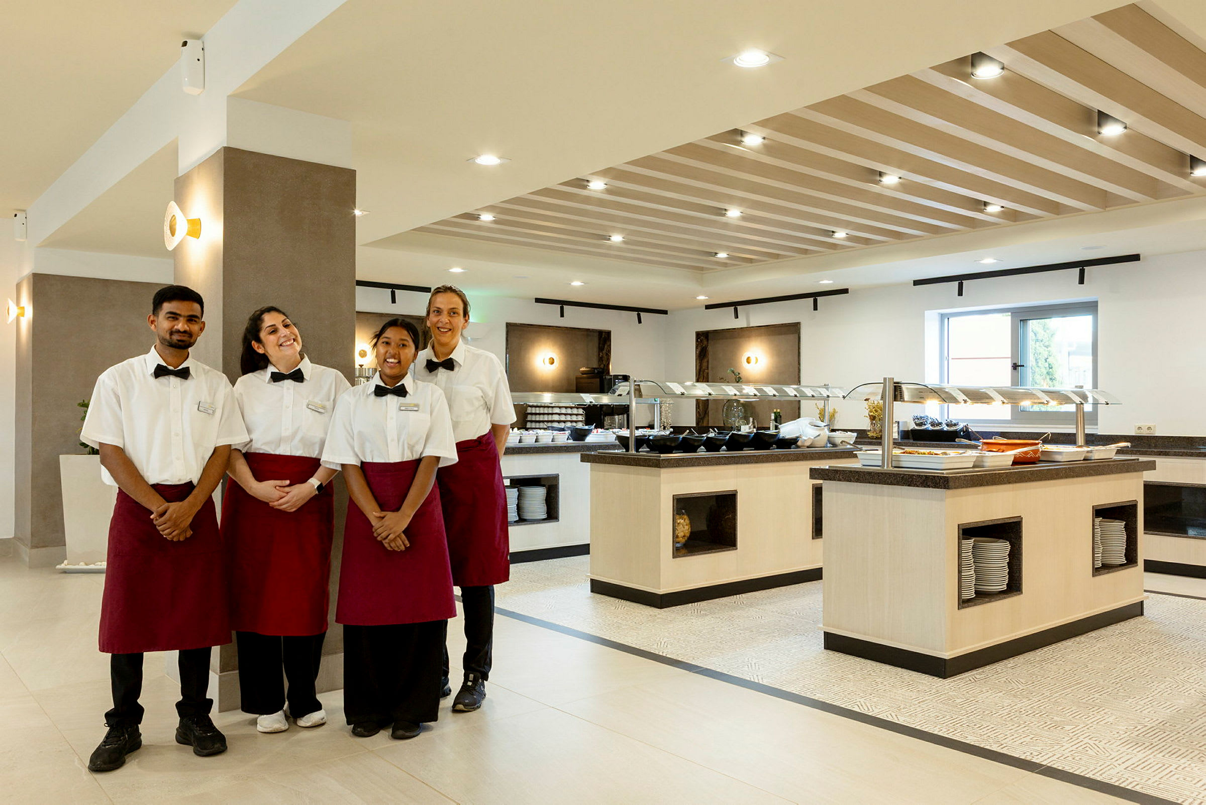 Fire personer i uniform står foran en buffet i en spisesal. (AI-generert tekst)