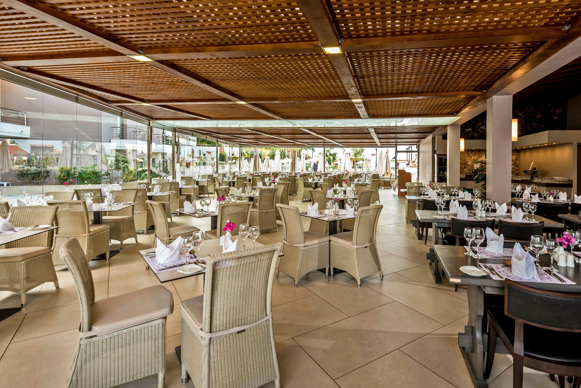 Restaurant med dekkede bord og stoler under en trepergola. (AI-generert tekst)