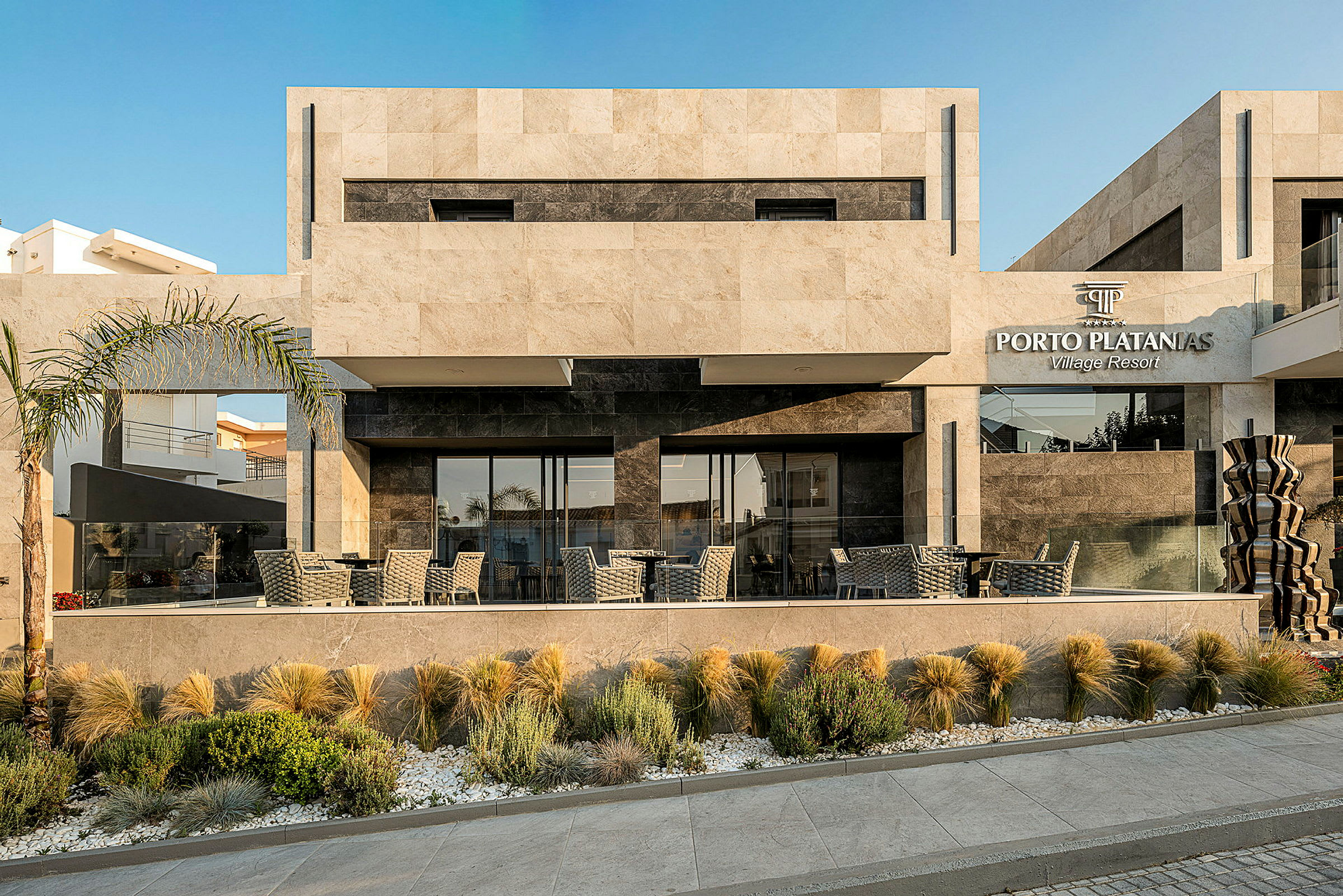 Eksteriør av Porto Platanias Village Resort bygning med moderne design og utendørs servering. (AI-generert tekst)