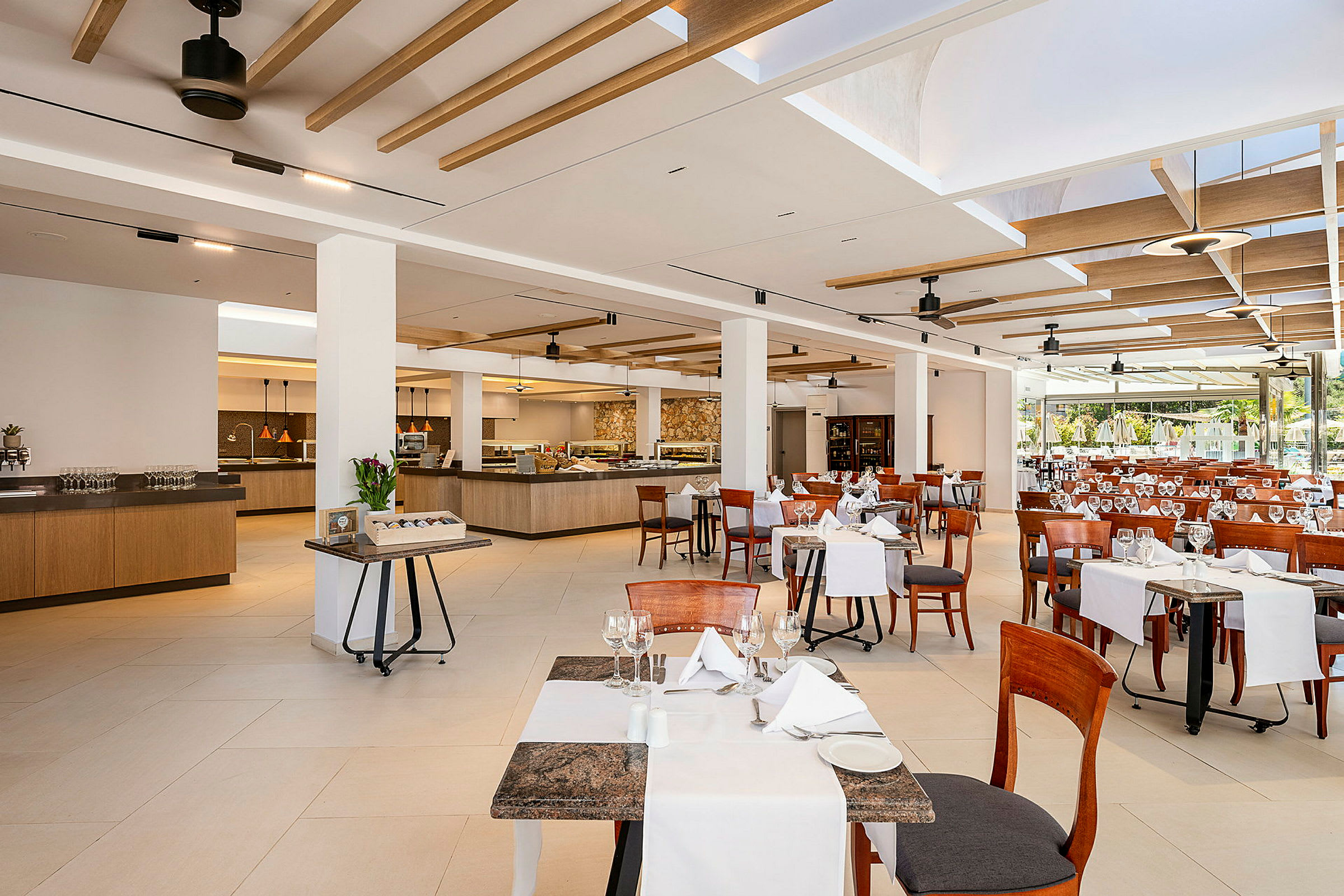 Bilde av en romslig restaurant med dekkede bord og stoler samt serveringsområder i bakgrunnen. (AI-generert tekst)