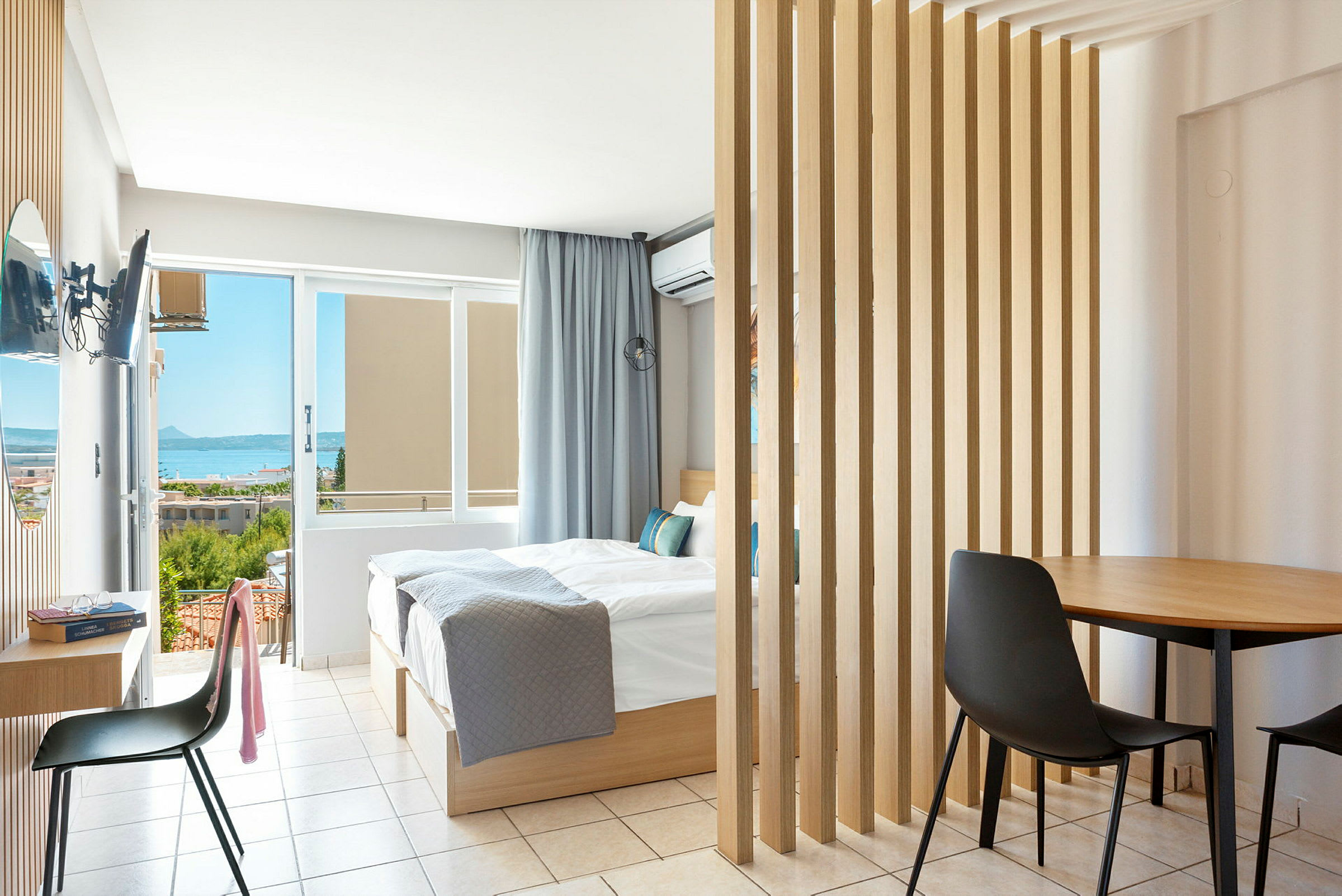 Et lyst hotellrom med dobbeltseng og utsikt mot havet. (AI-generert tekst)