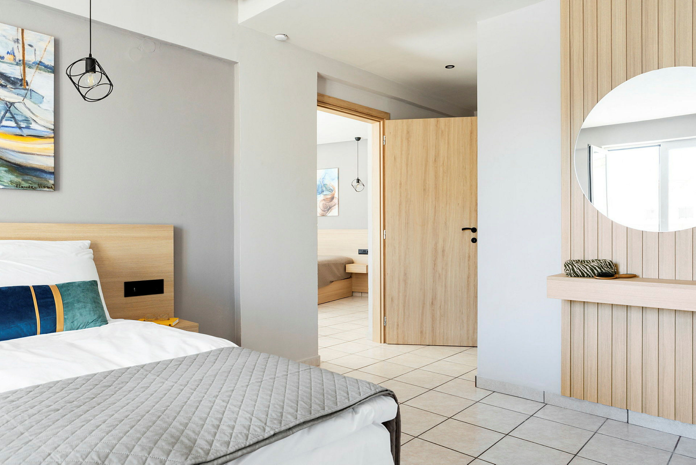 Interiøret i et hotellrom med en seng, et speil og en åpen dør. (AI-generert tekst)