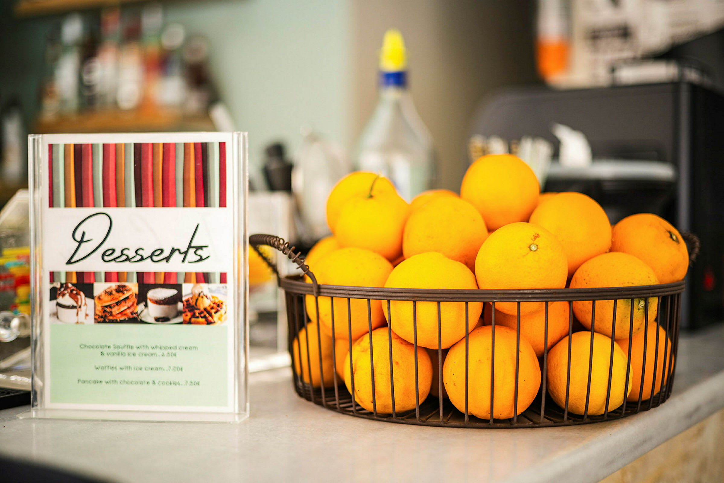 En kurv med appelsiner står ved siden av en dessertmeny. (AI-generert tekst)