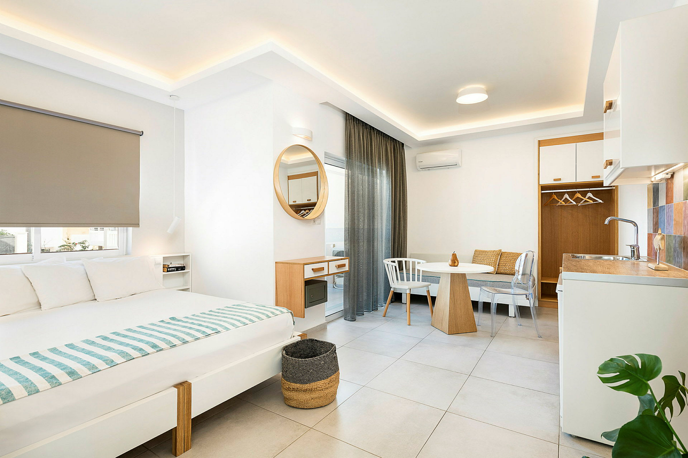 Interiør av et moderne hotellrom med seng, spisebord og liten kjøkkenkrok. (AI-generert tekst)