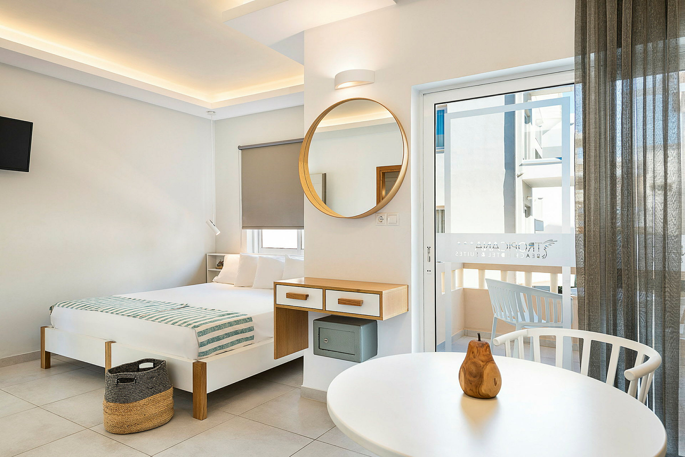 Moderne innredet hotellrom med seng, speil og balkongdør. (AI-generert tekst)