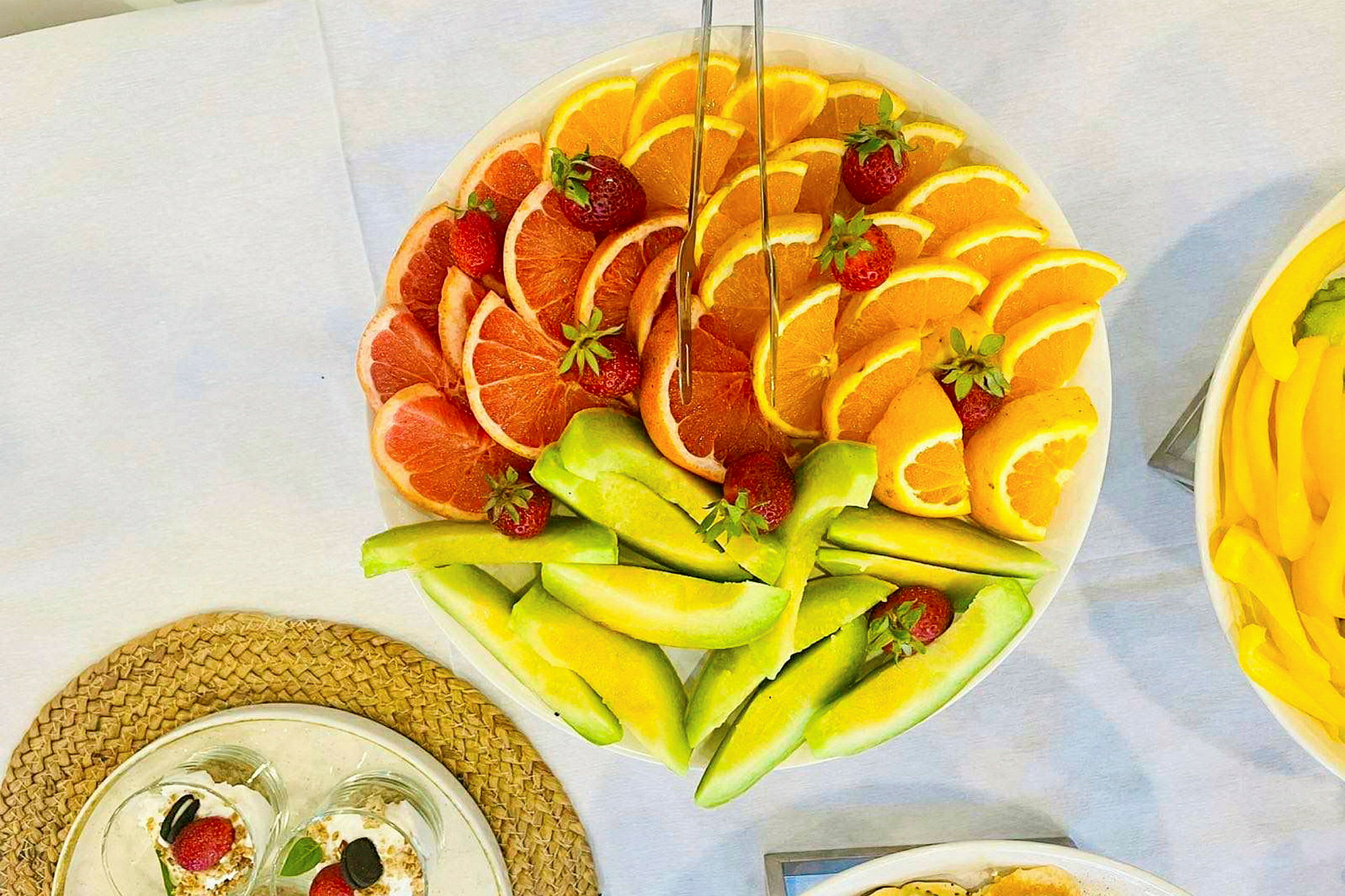 En tallerken med skåret frukt som grapefrukt, appelsiner og melon, dekorert med jordbær. (AI-generert tekst)