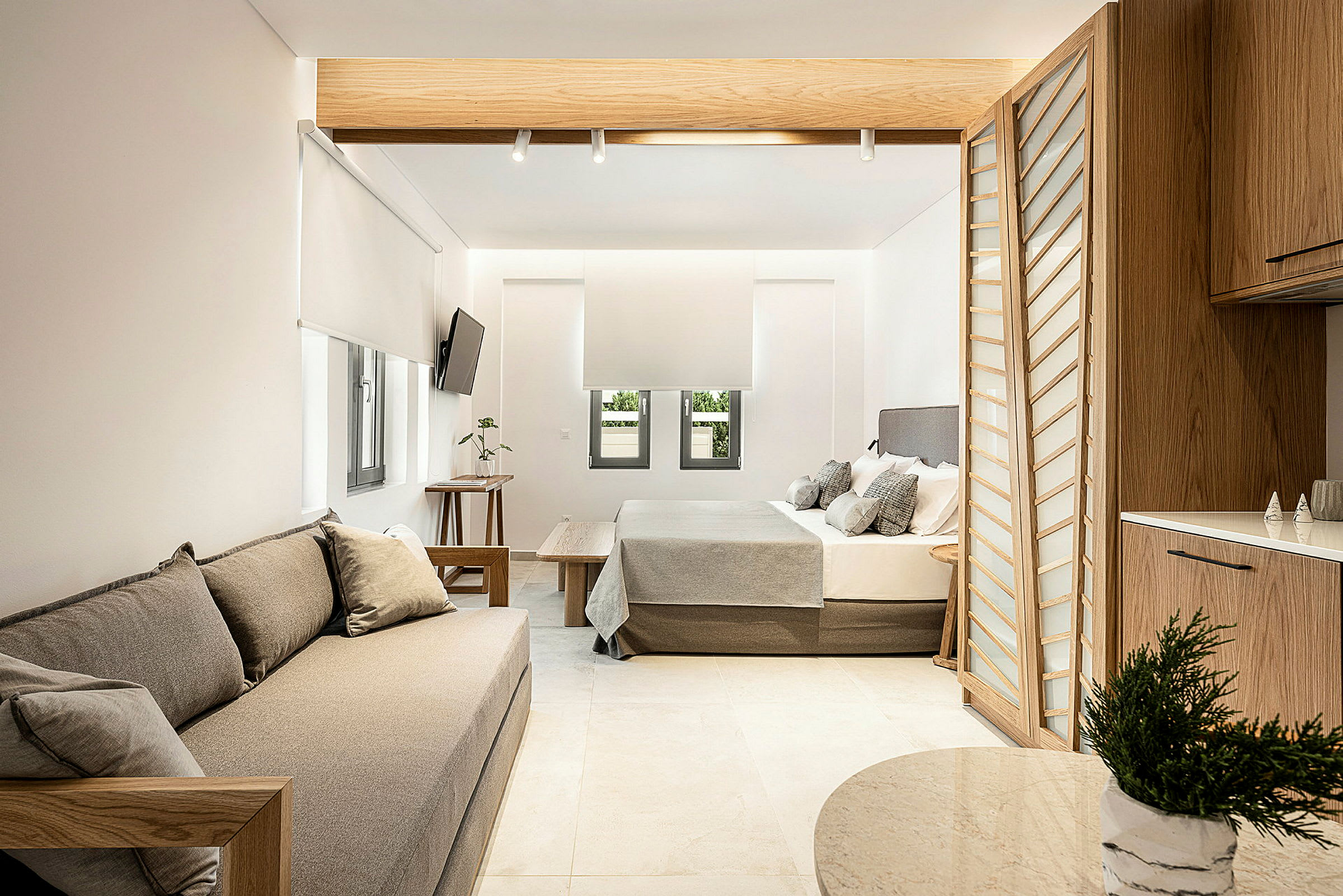 Moderne innredet hotellsuite med sittemøbler, seng og kjøkkenområde. (AI-generert tekst)