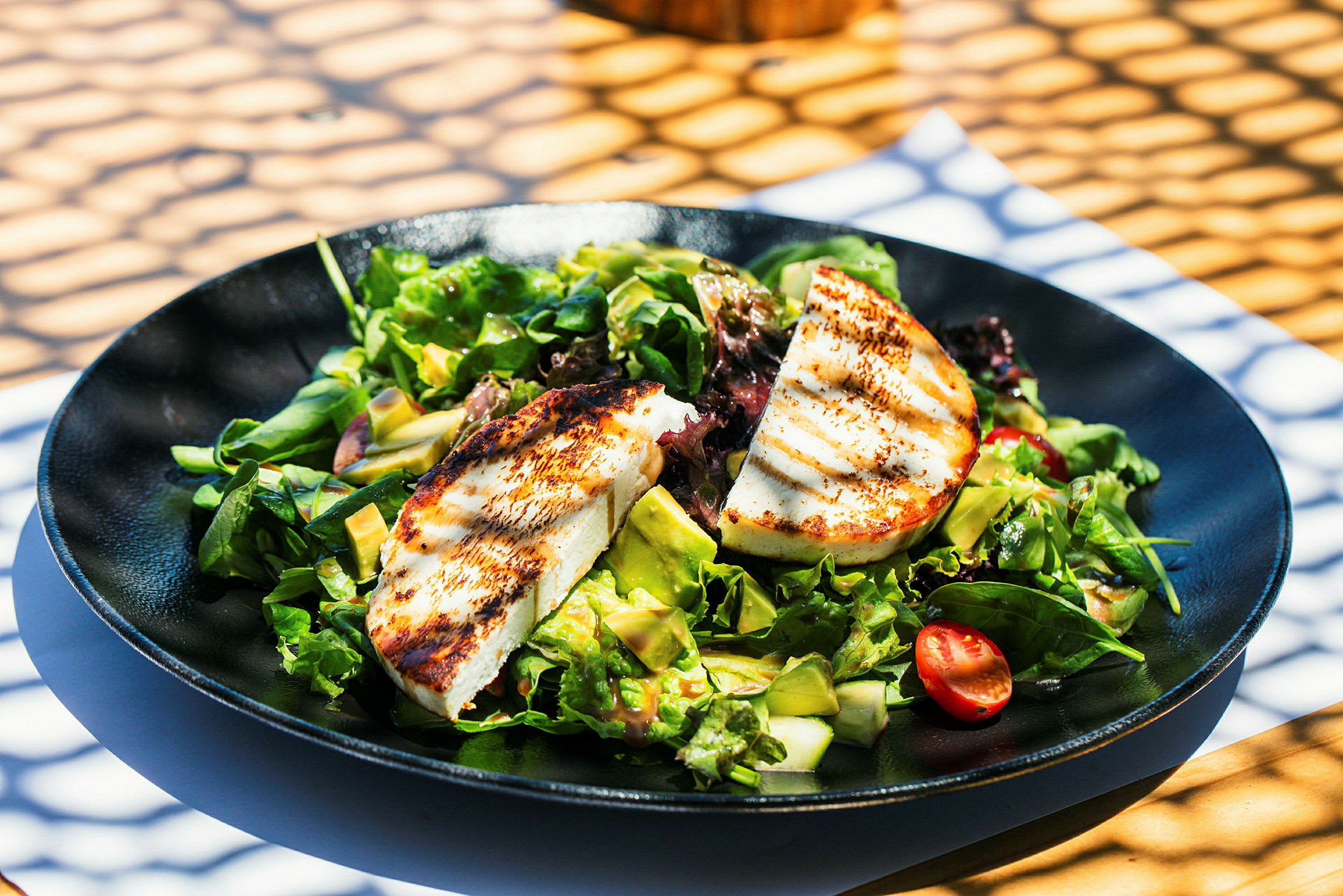 En salatrett med grillet ost, tomater og avokado. (AI-generert tekst)