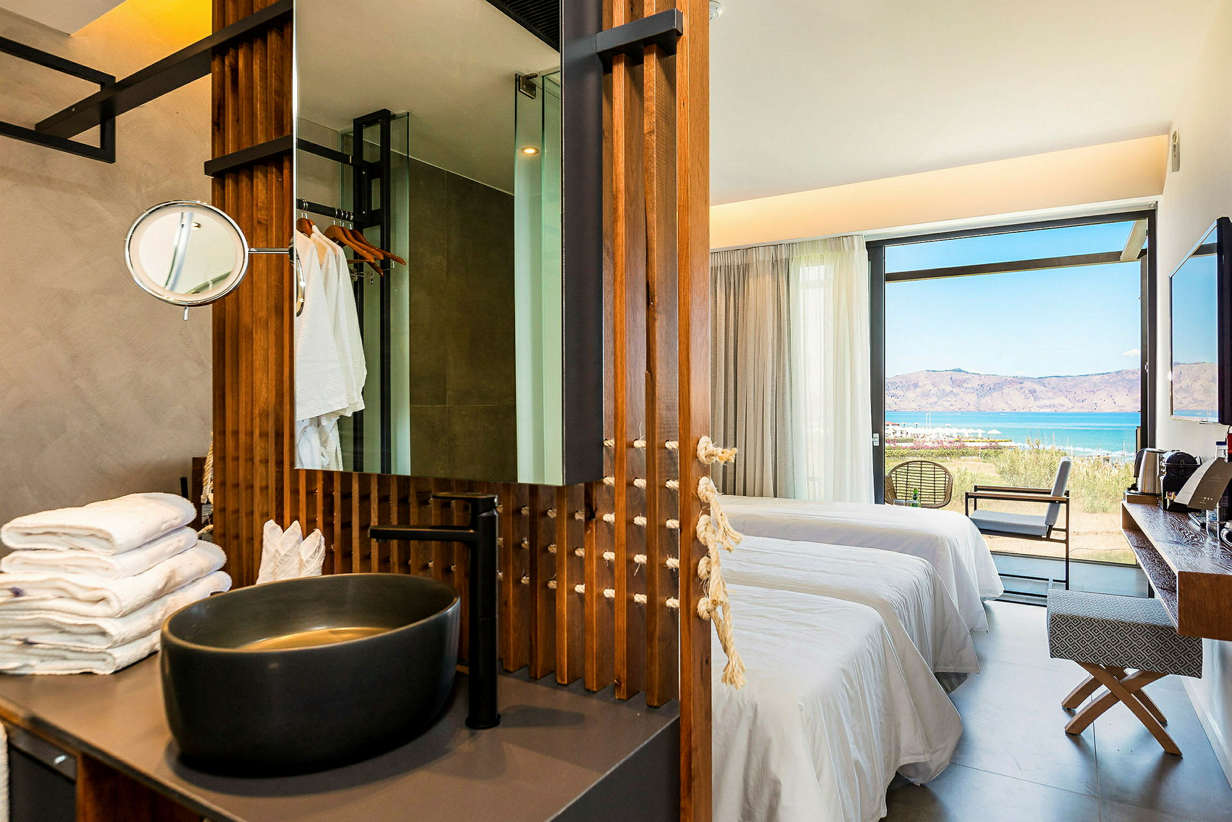 En moderne hotellsuite med skålformet vask, senger og utsikt over havet. (AI-generert tekst)