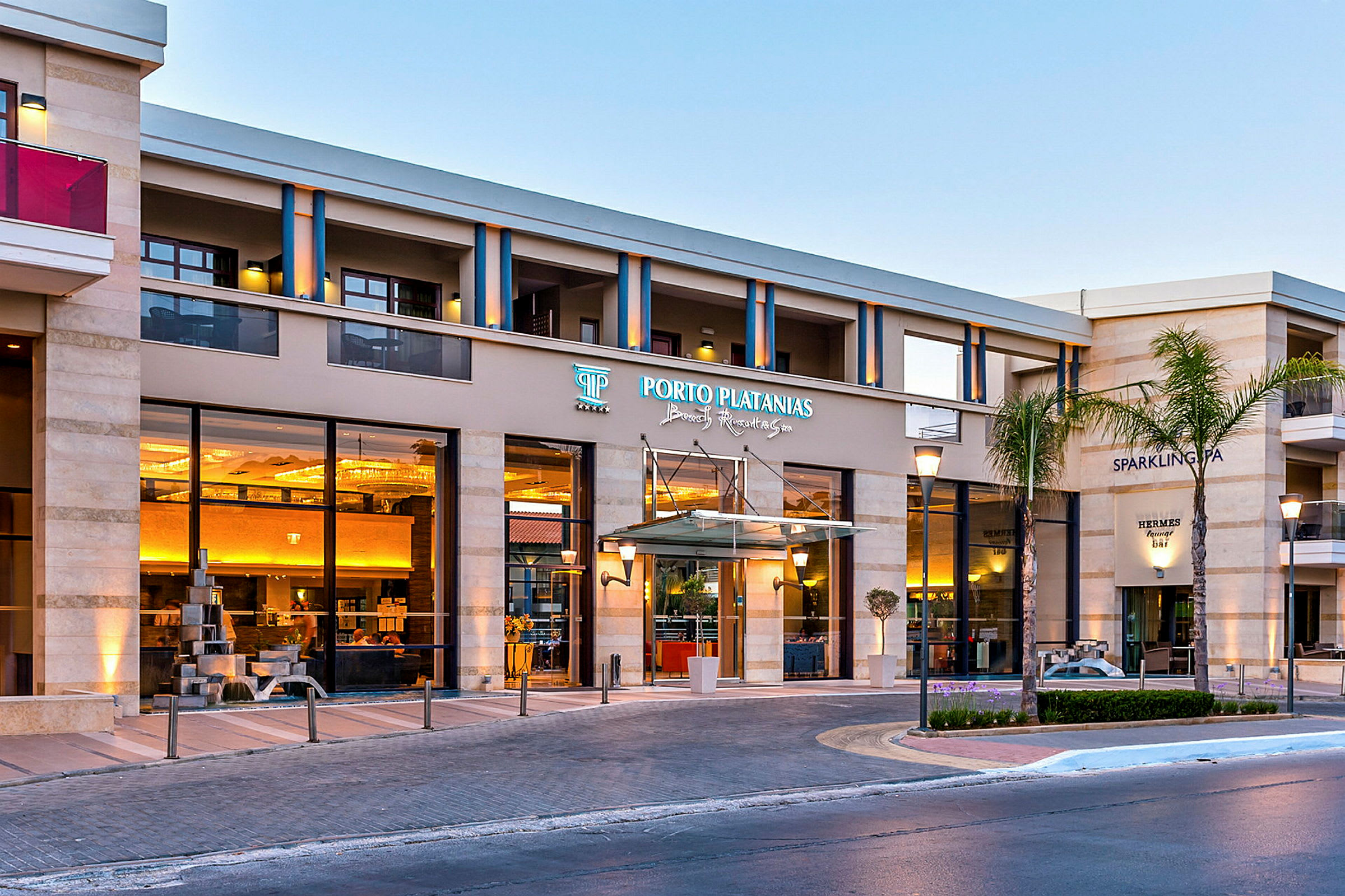 Hotellbygning med inngangskiltet Porto Platanias Beach Resort & Spa. (AI-generert tekst)
