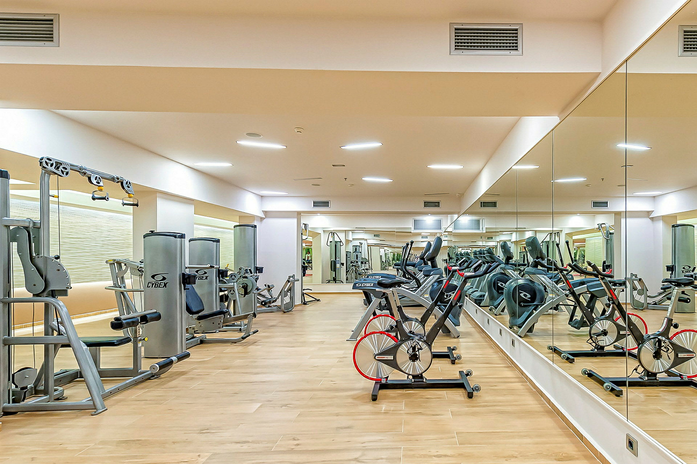 Gym med treningsmaskiner og speil langs veggene. (AI-generert tekst)