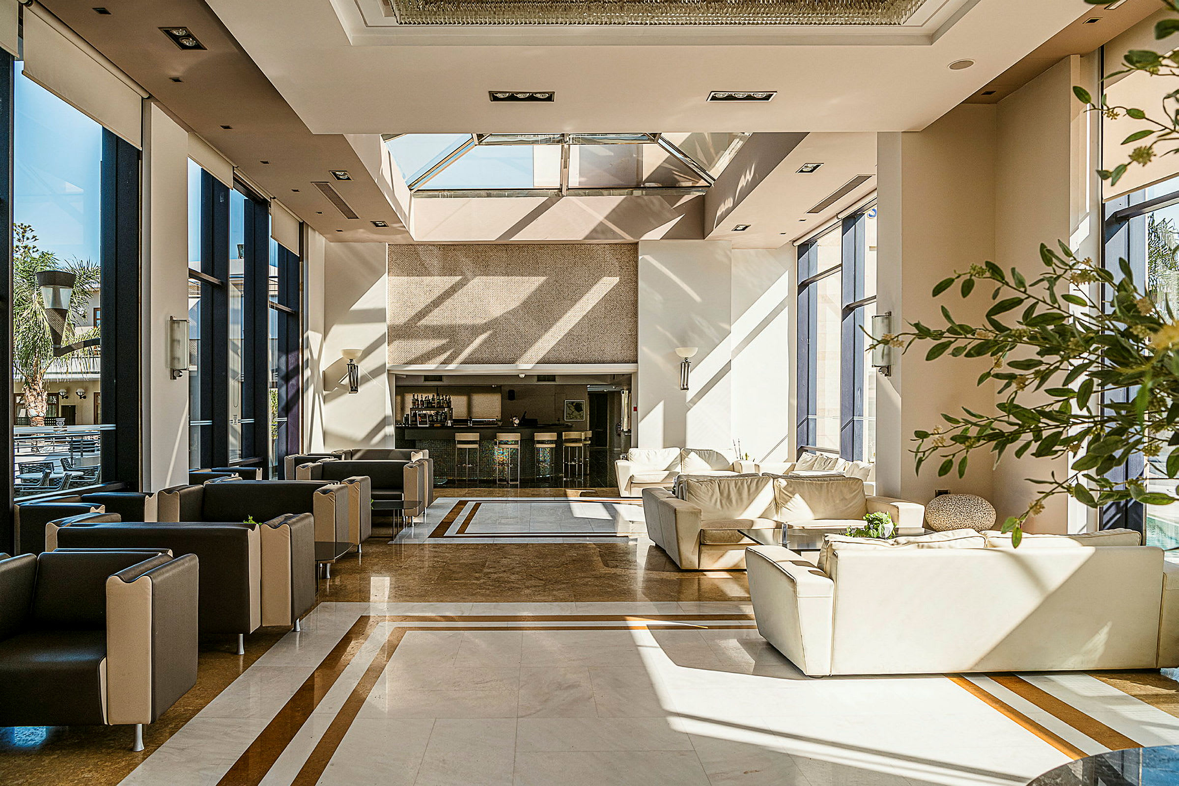 En lys og moderne innredet hotellobby med store vinduer, komfortable sittemøbler og en resepsjonsdisk. (AI-generert tekst)