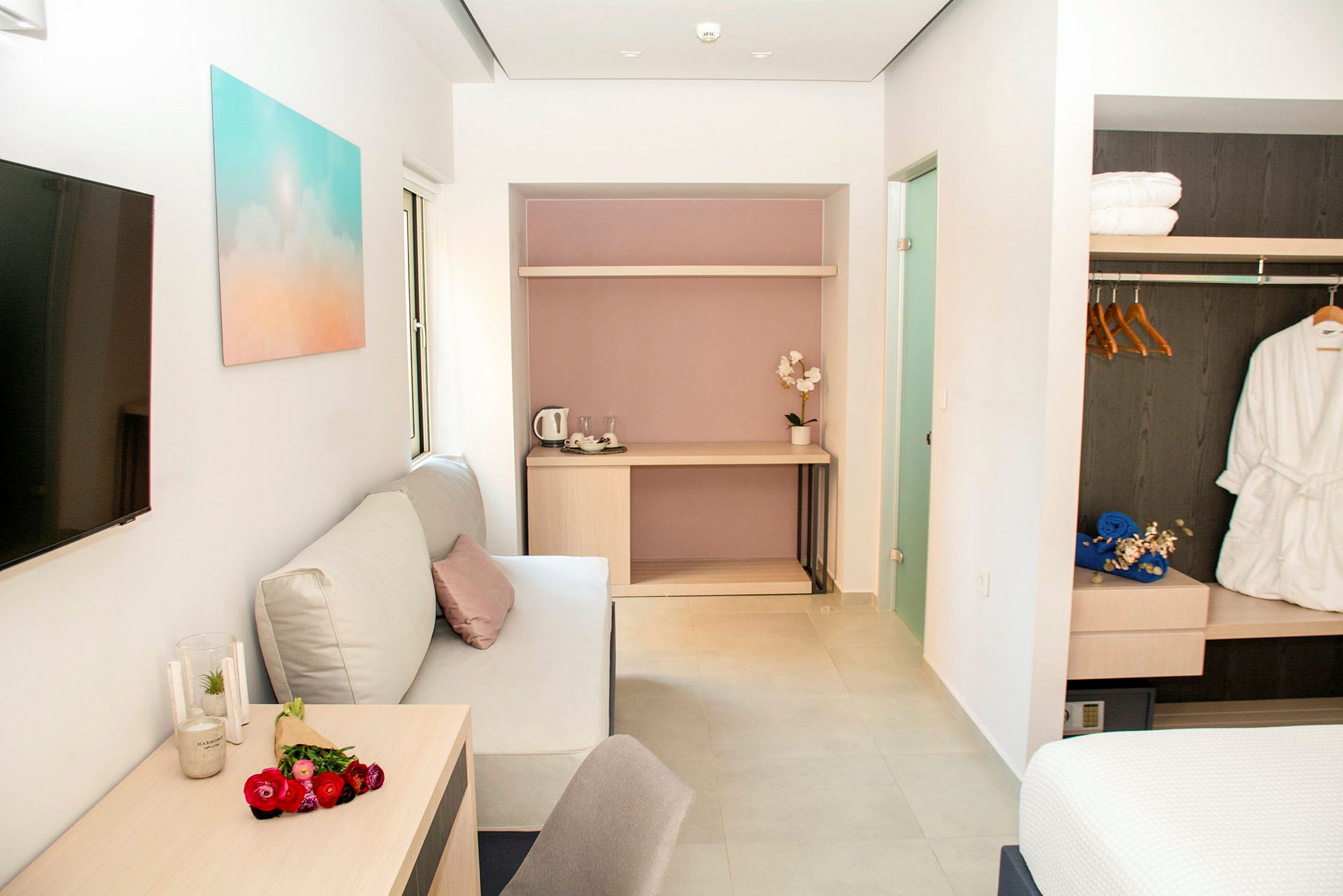 Et moderne hotellrom med sofa, bord og garderobe. (AI-generert tekst)