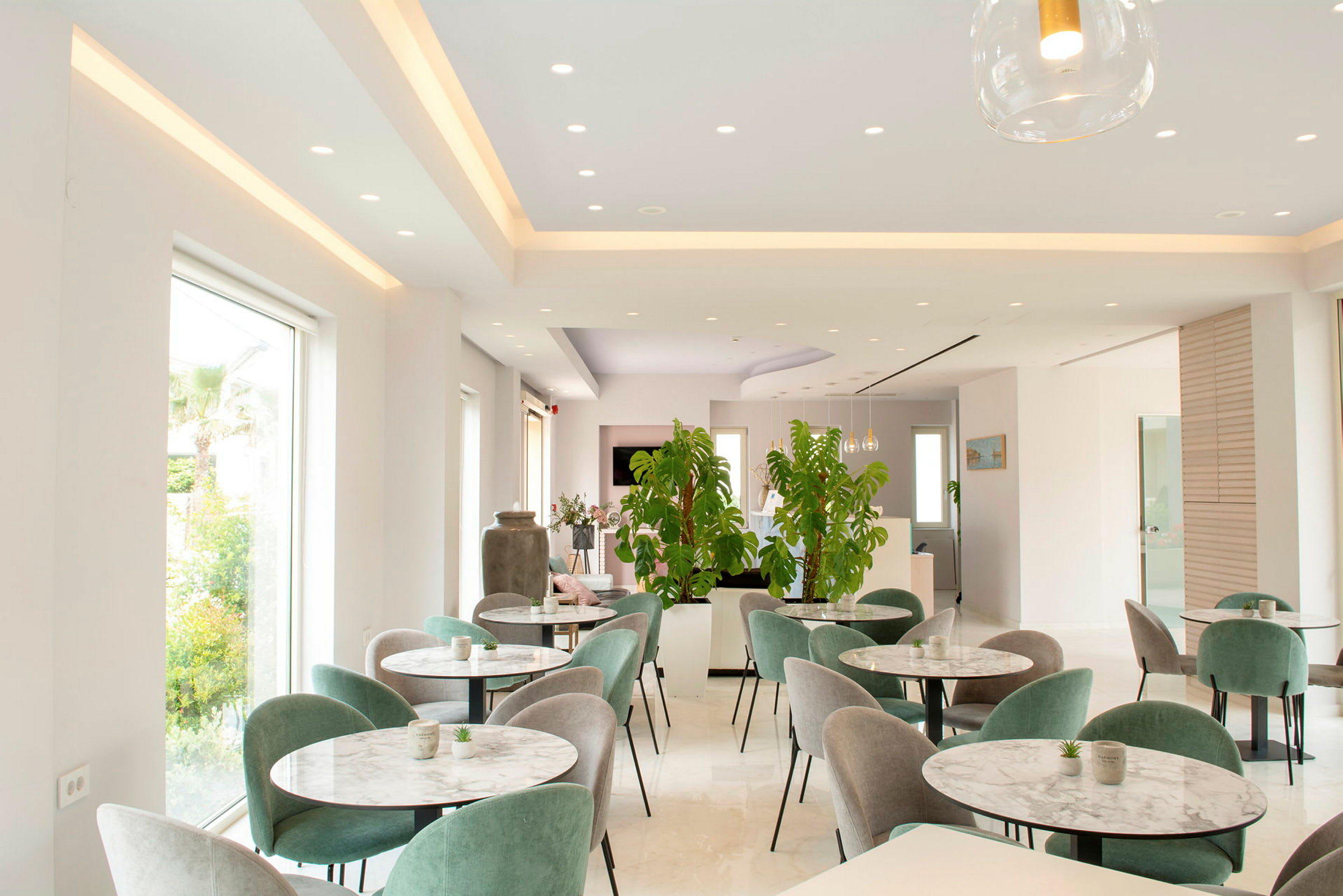 Moderne innredet restaurant med grønne planter og flere bord. (AI-generert tekst)