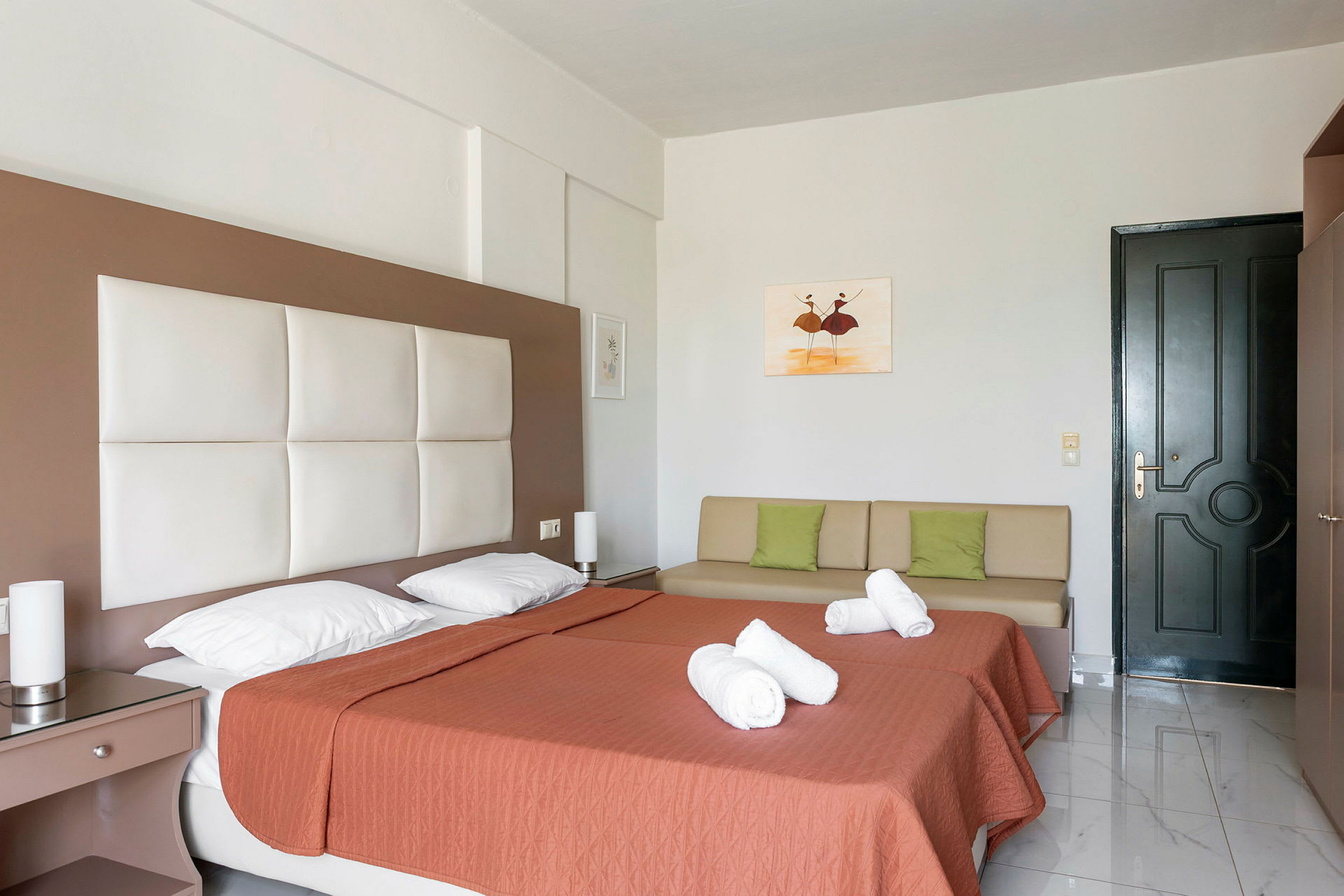 Hotellrom med to enkeltsenger, putetrekk, en sofa og en dør. (AI-generert tekst)