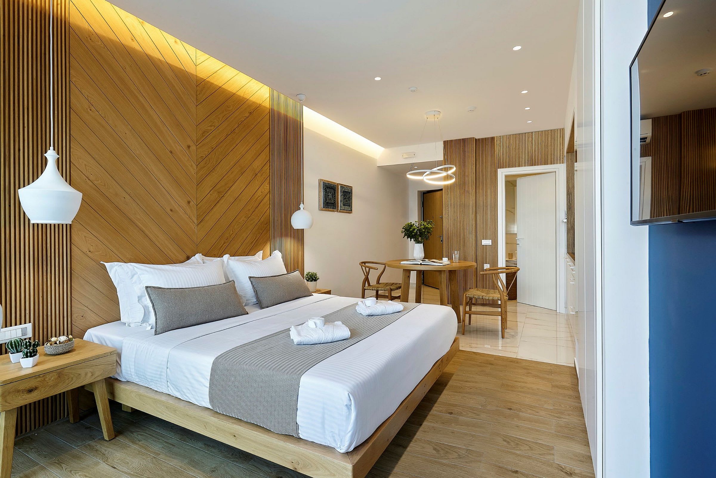 Et godt opplyst hotellrom med en dobbeltseng og et lite spisebord. (AI-generert tekst)