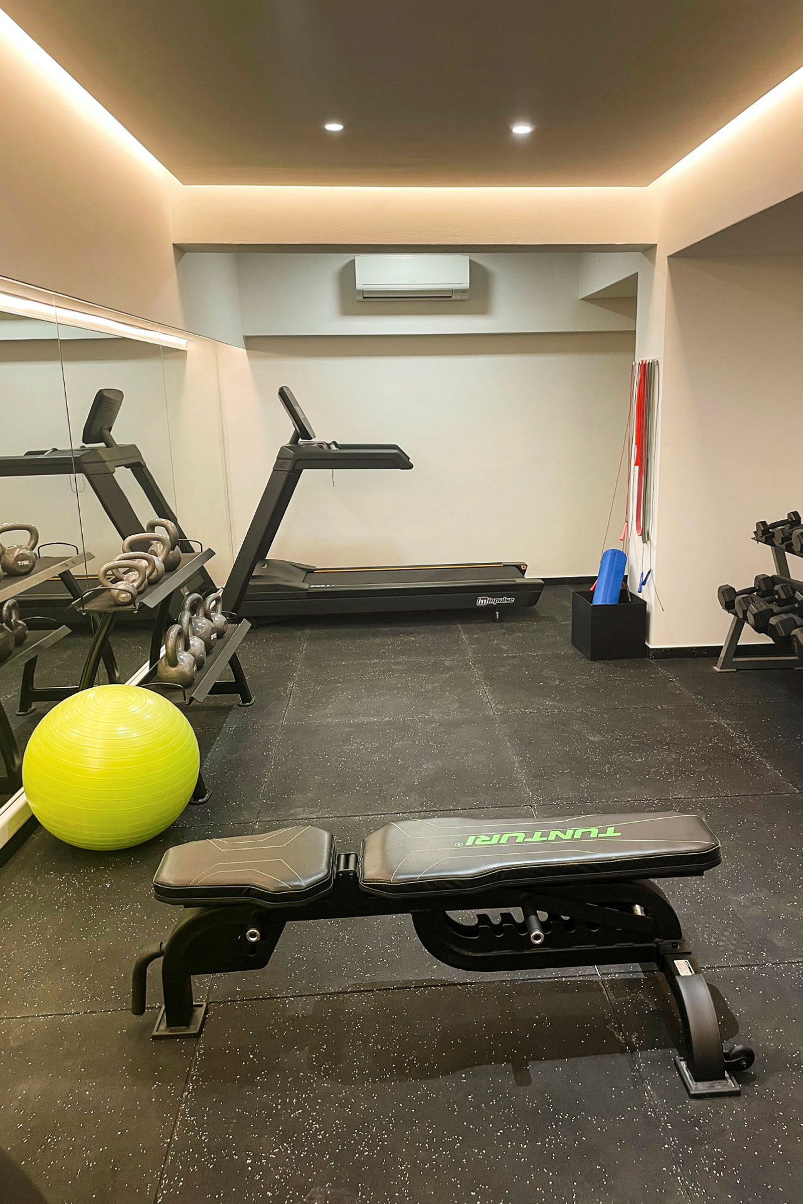 Et treningsrom med tredemølle, treningsbenk, kettlebells og pilatesball. (AI-generert tekst)