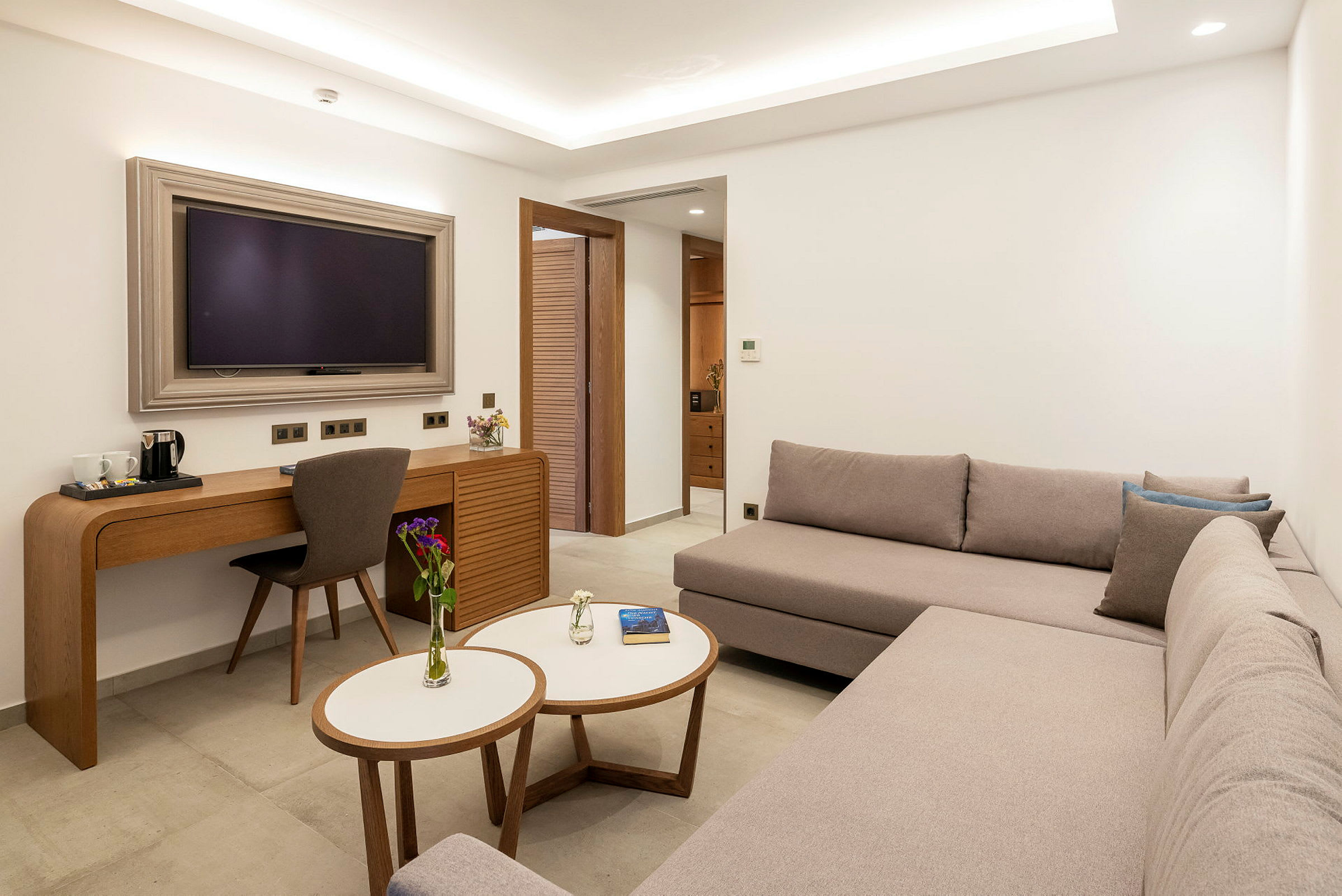 Et moderne hotellrom med en sofa, et skrivebord og en TV. (AI-generert tekst)