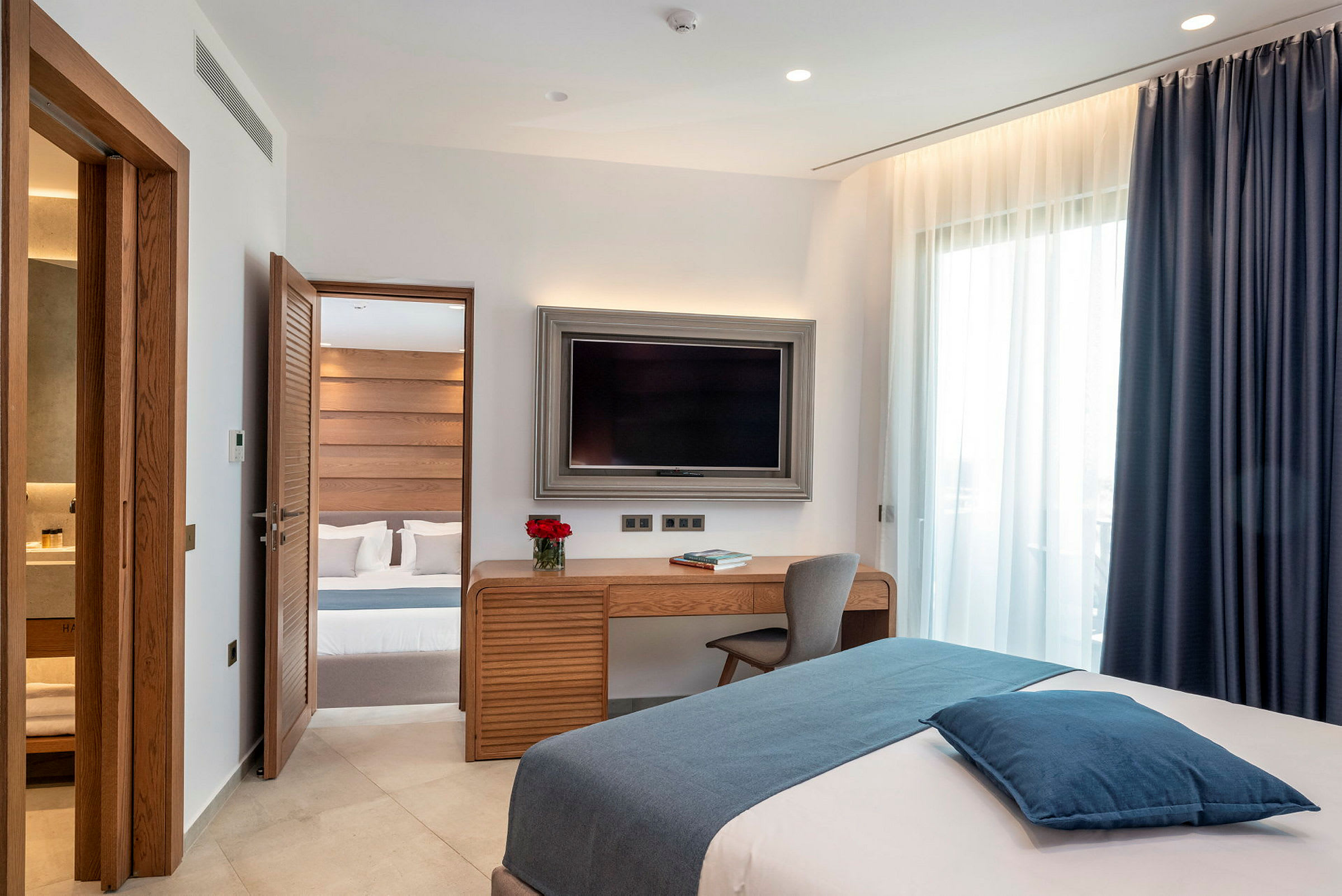 Et hotellrom med moderne innredning, en seng, et skrivebord og en TV. (AI-generert tekst)