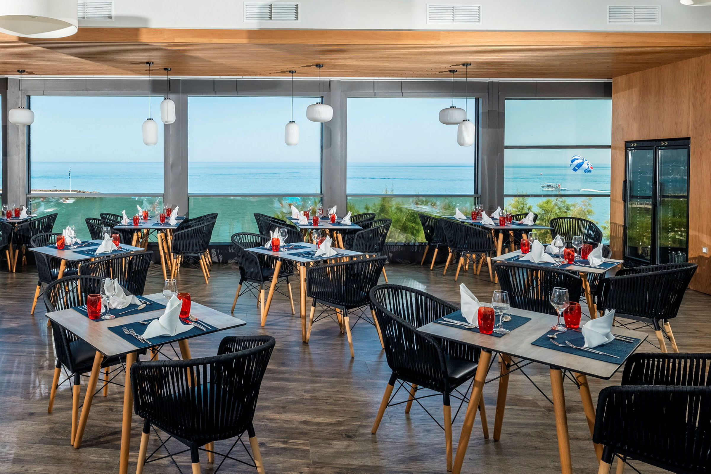 En restaurant med dekkede bord og utsikt over havet gjennom store vinduer. (AI-generert tekst)