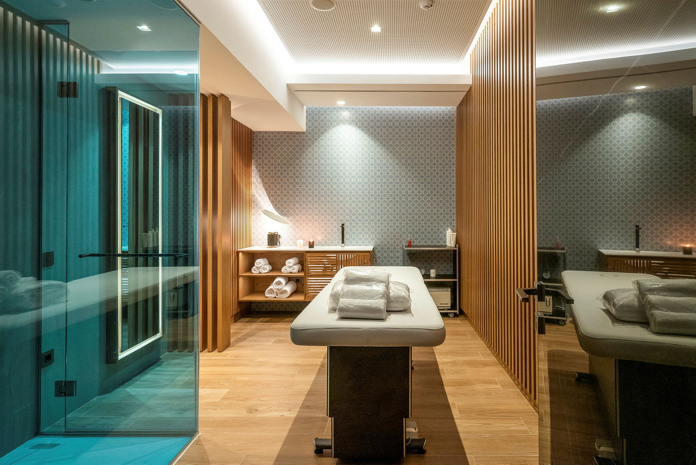Et moderne spa-rom med en massasjebenk, håndklær og tre detaljer. (AI-generert tekst)