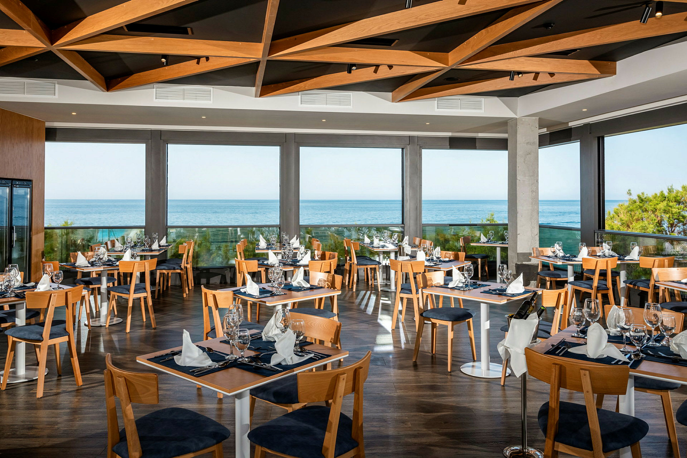 En moderne restaurant med store glassvinduer og havutsikt. (AI-generert tekst)
