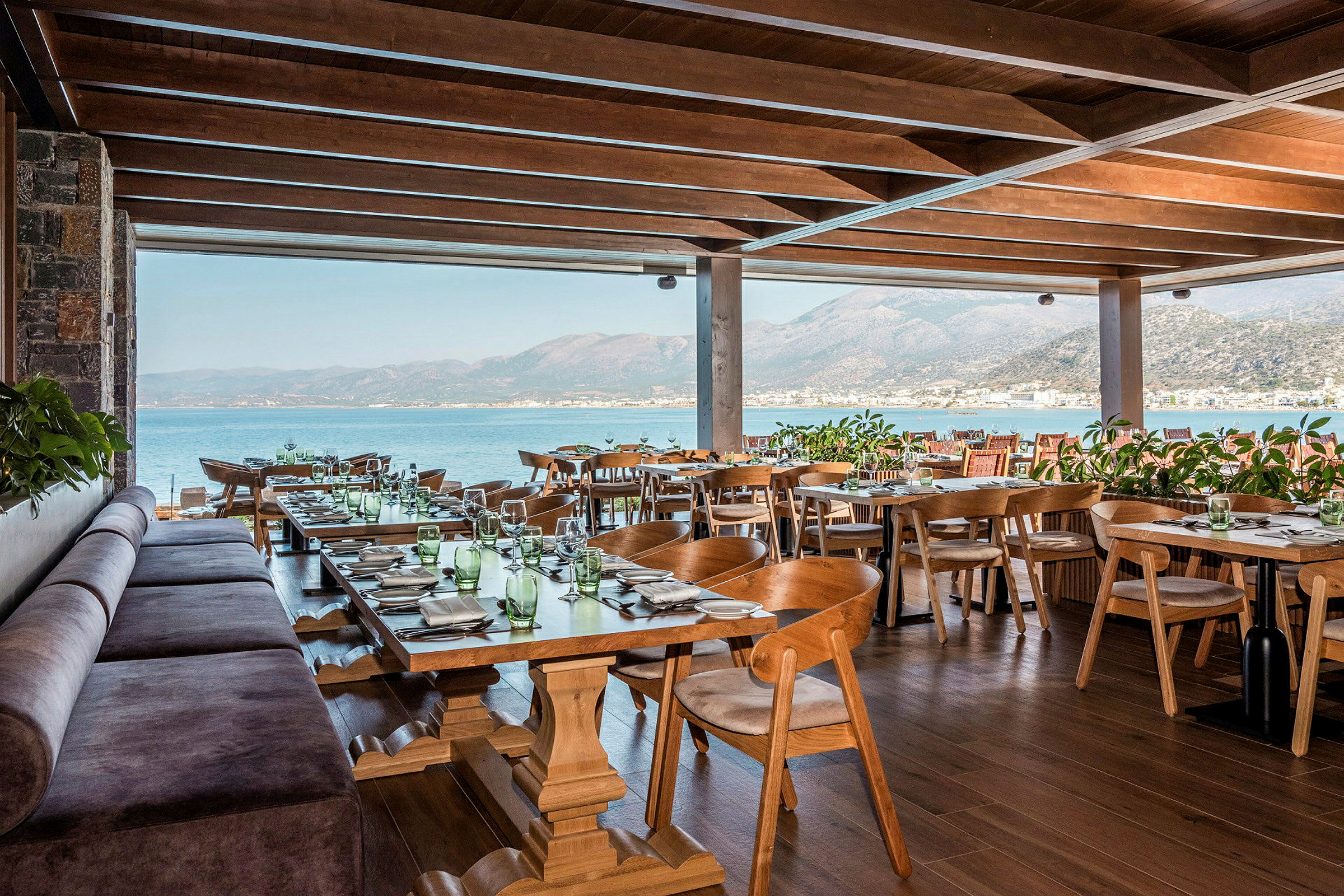 En restaurant med trebord og stoler samt sjøutsikt. (AI-generert tekst)