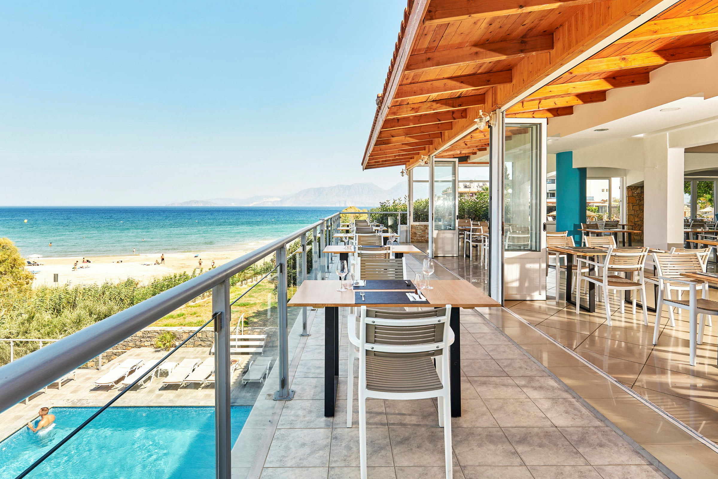 Utendørs servering på en restaurant med utsikt over havet og stranden. (AI-generert tekst)