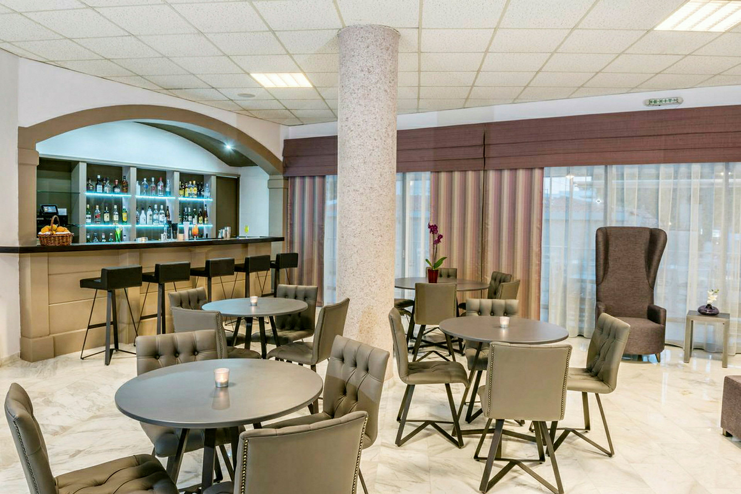 Bilde av en hotellbar med flere bord og stoler, samt en bardisk med barstoler. (AI-generert tekst)