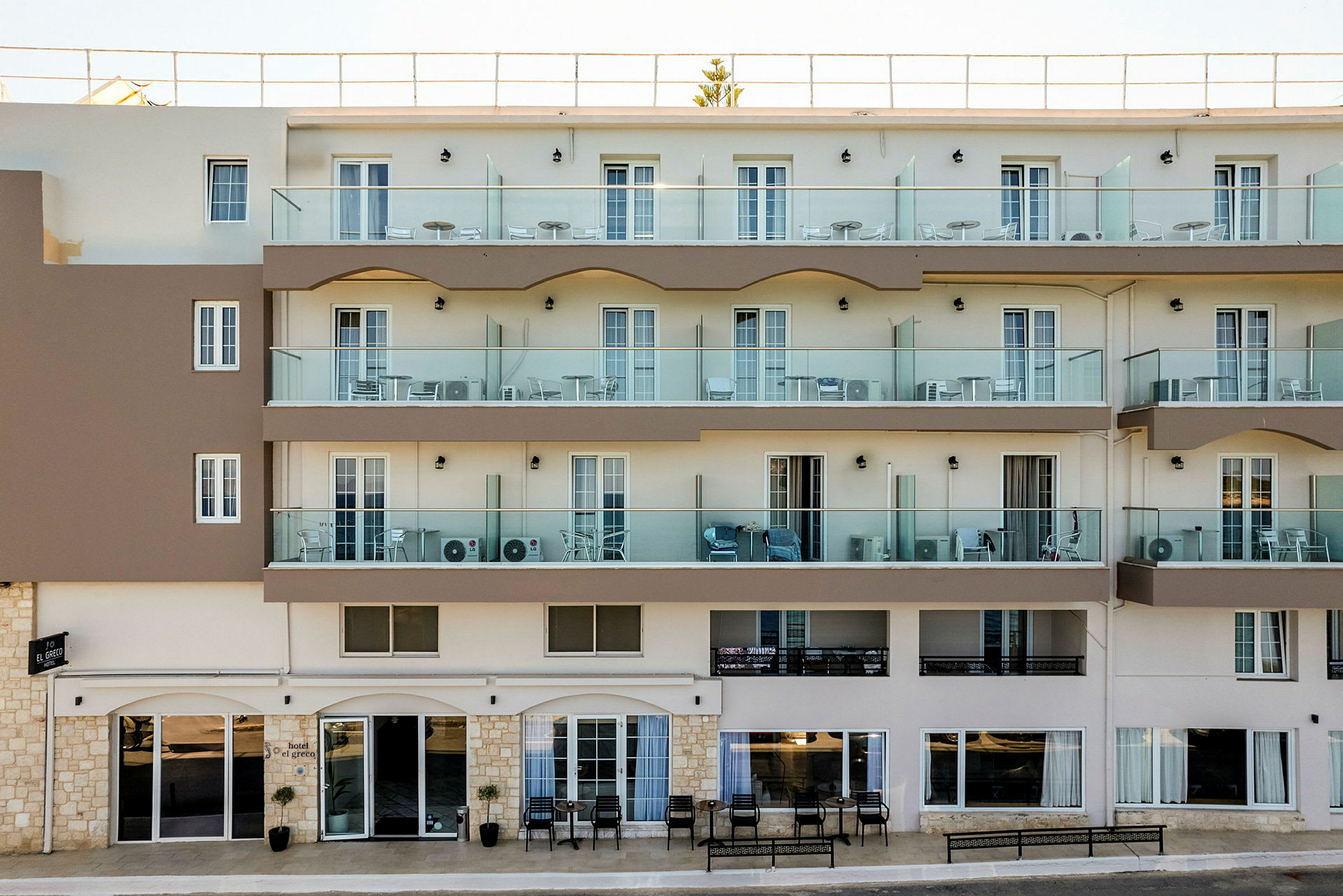 Hotellfasade med balkonger og inngang på bakkeplan. (AI-generert tekst)