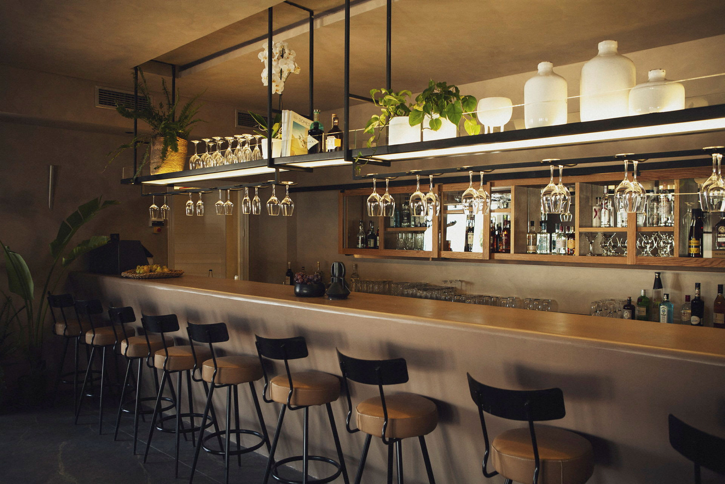 En bar med opphengte vinglass, stoler og oppbevaringsområder. (AI-generert tekst)