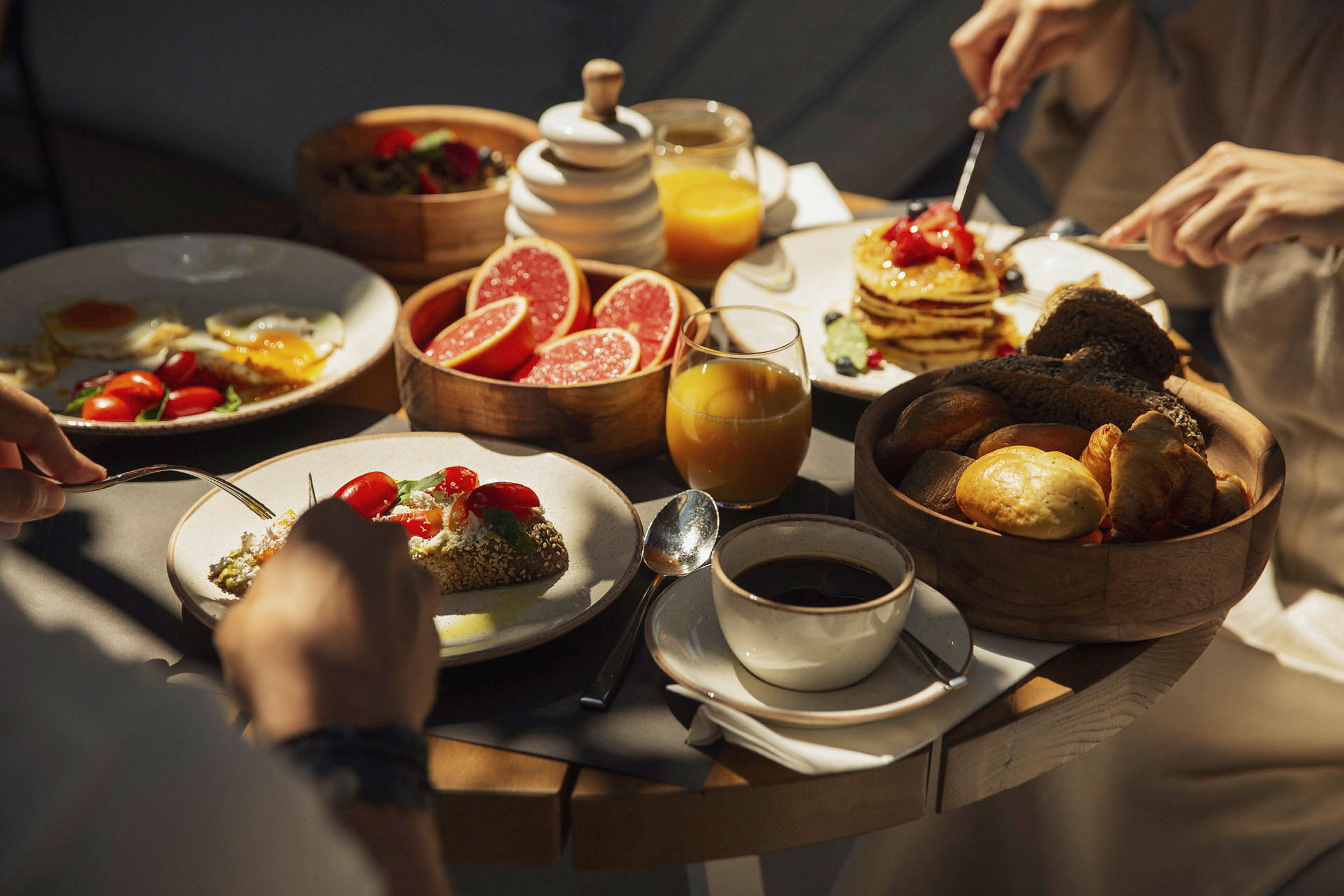 En frokost med ulike matvarer, inkludert pannekaker, grapefruktskiver, brød og kaffe. (AI-generert tekst)