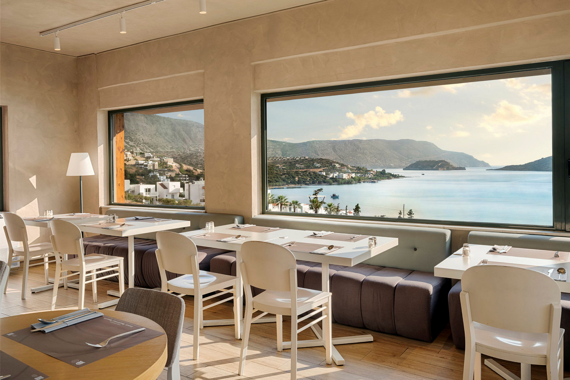 Restaurant med dekkede bord og panoramautsikt over kyst og fjell. (AI-generert tekst)