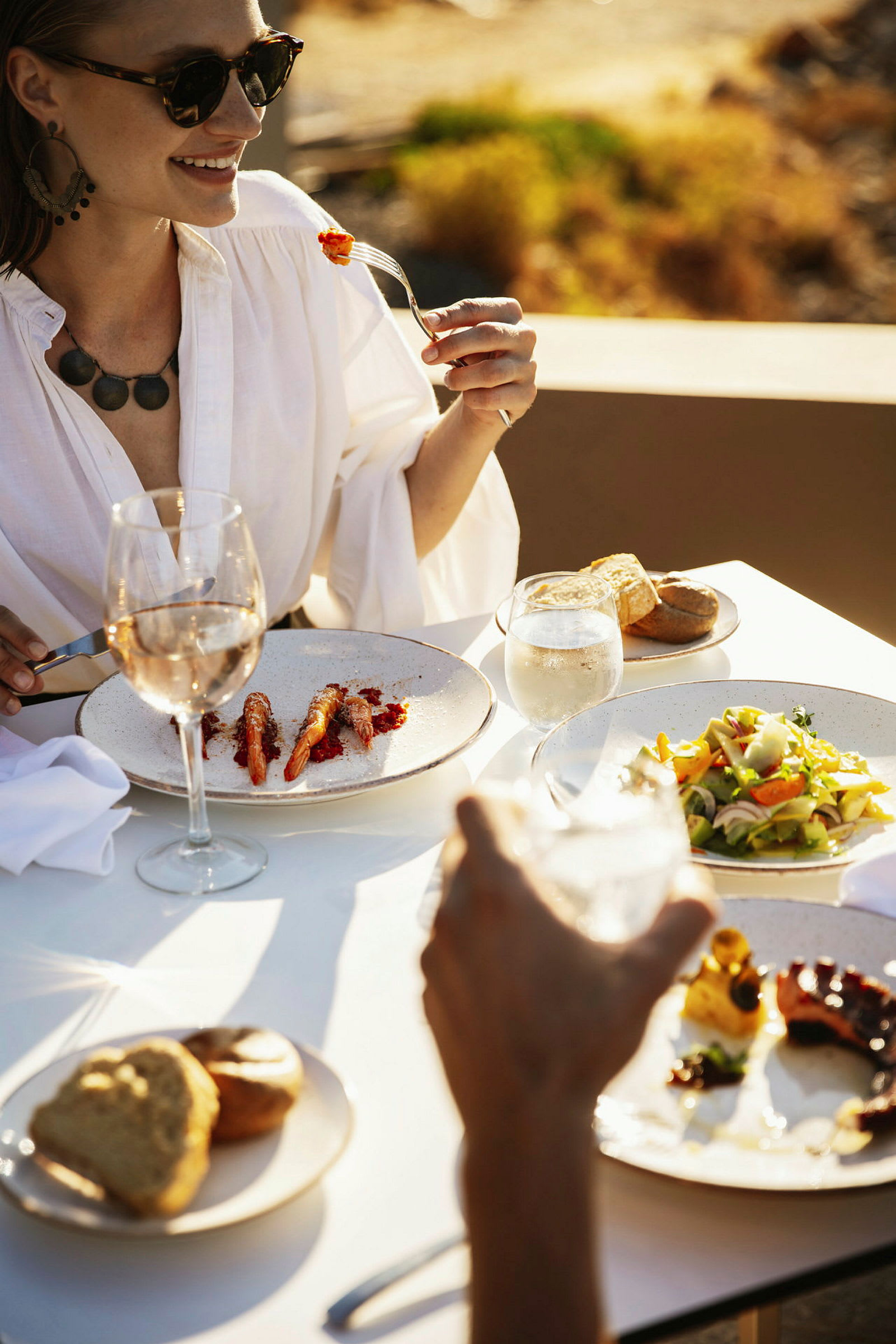 Person som sitter ved et bord med et måltid og et glass vin utendørs. (AI-generert tekst)