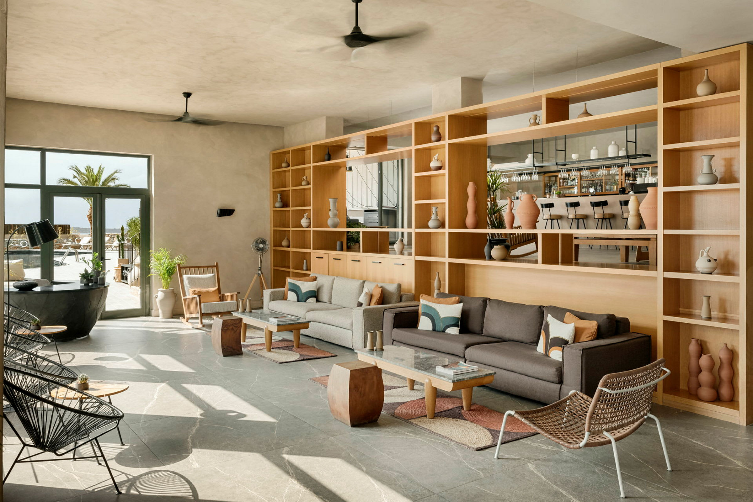 Et moderne loungeområde med sofaer og hyller, store vinduer og en bar i bakgrunnen. (AI-generert tekst)