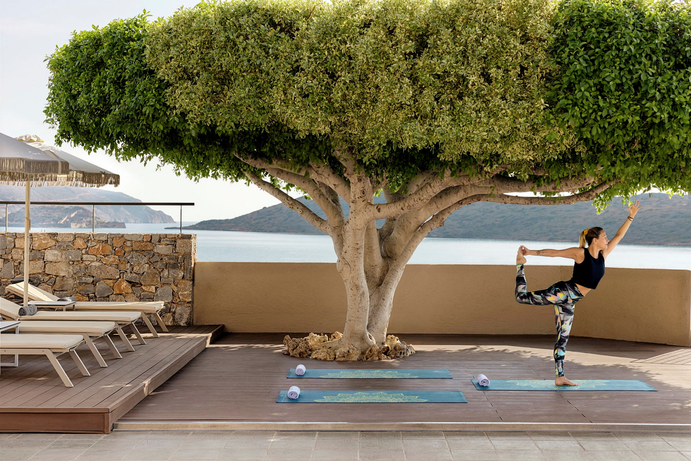En person utfører yoga på en uteplass med utsikt over havet. (AI-generert tekst)
