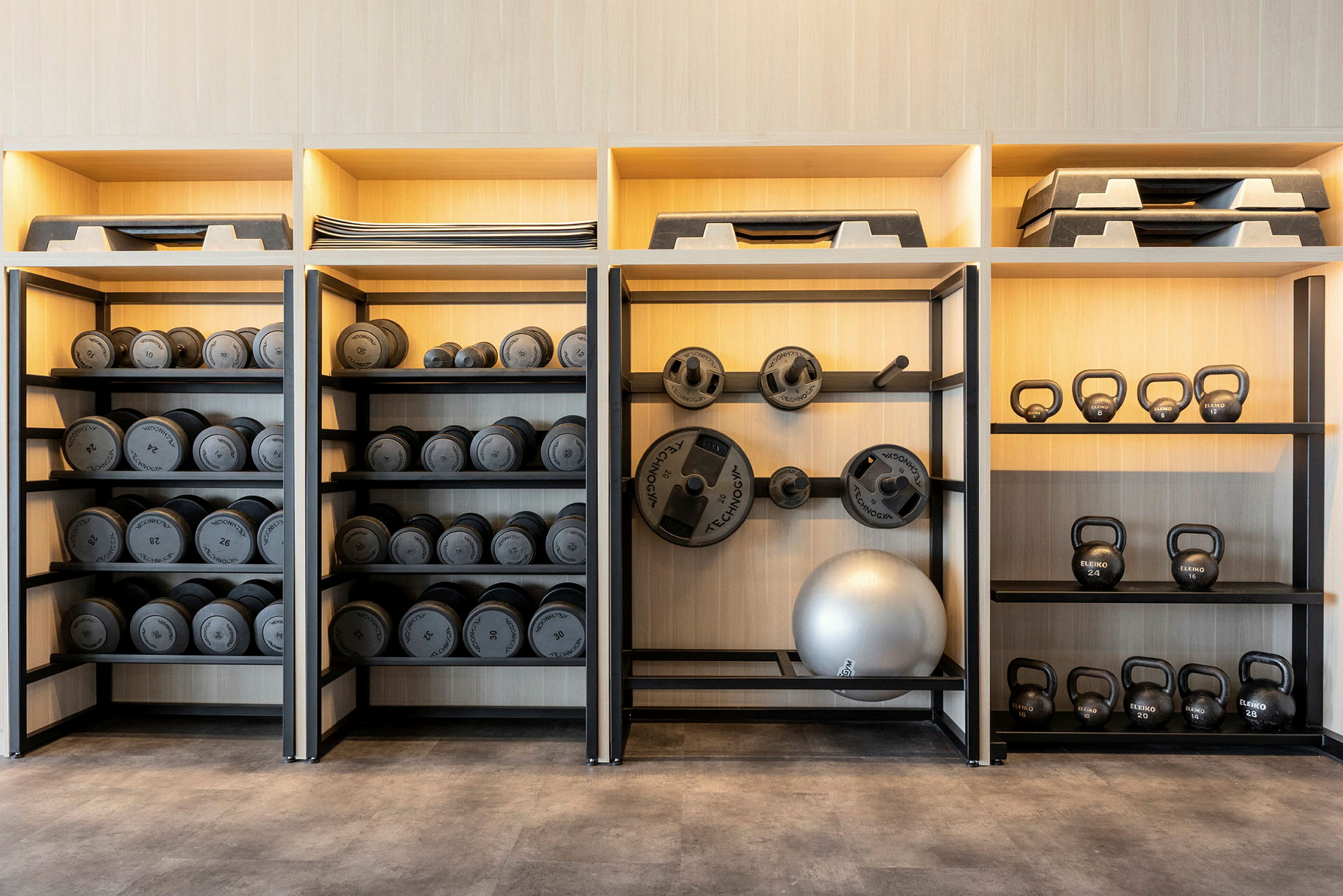 Hylle med manualer, vektskiver, kettlebells og treningsutstyr. (AI-generert tekst)